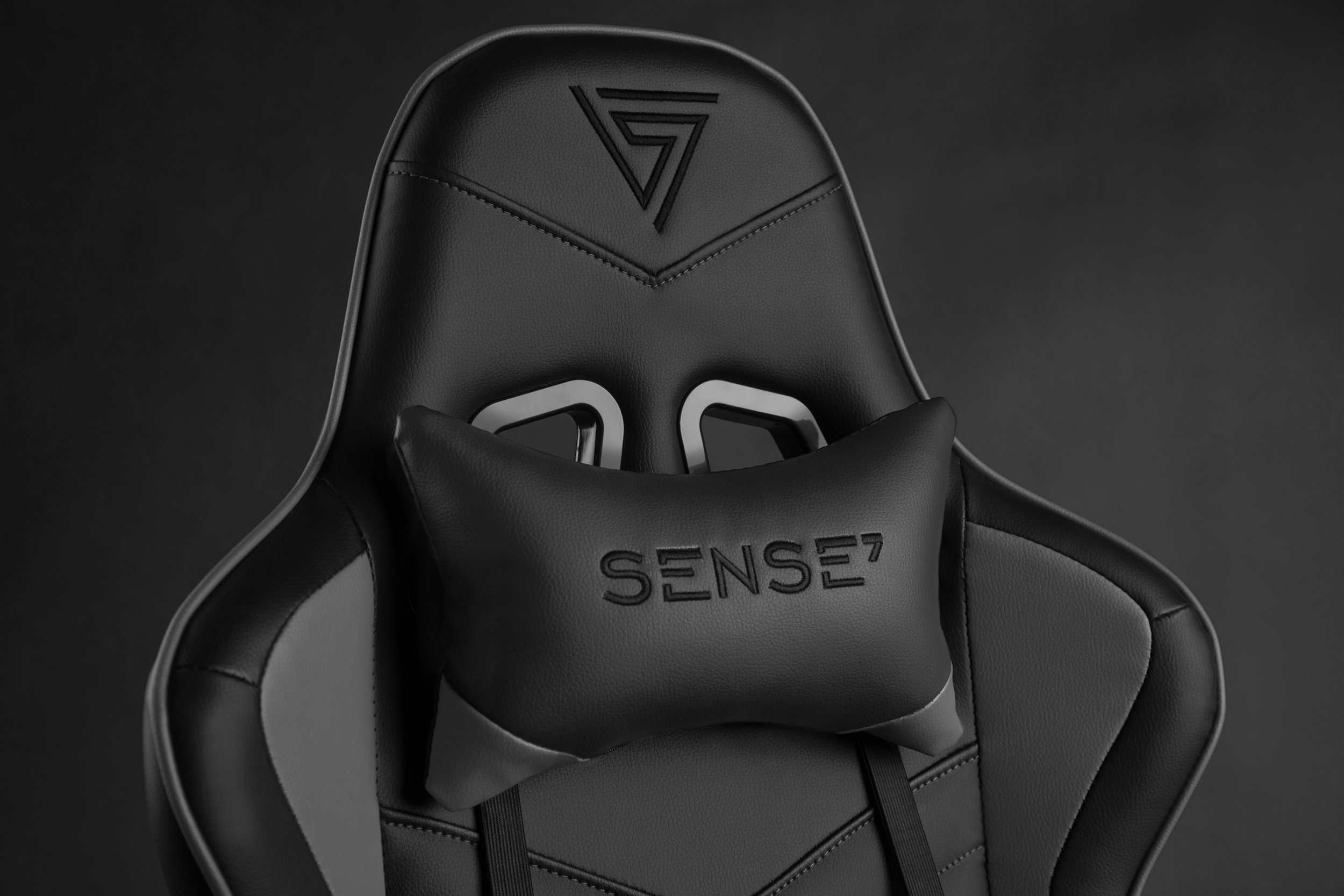 Silla gaming negra con reposacabezas. Logo en relieve en el respaldo.