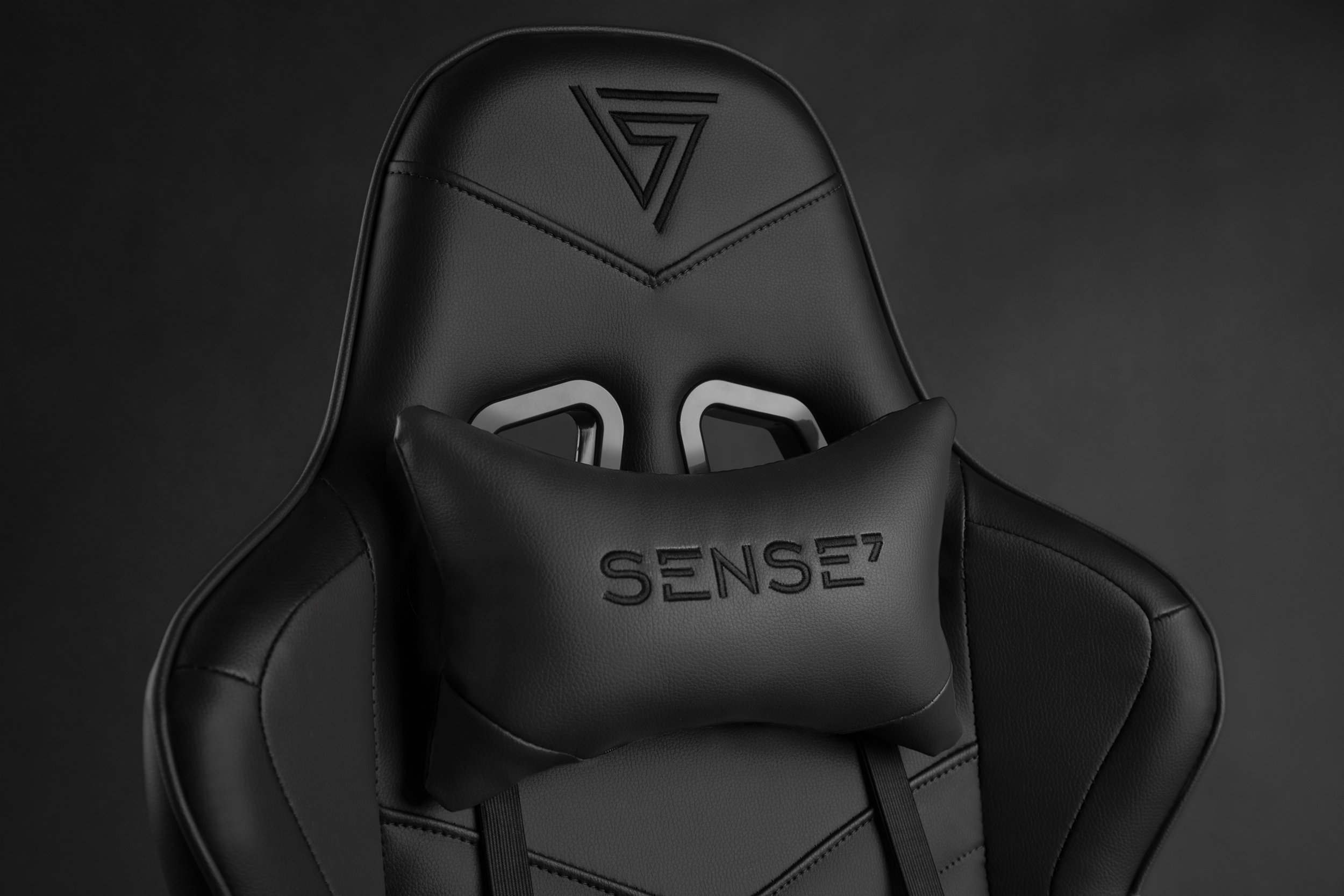 Silla gamer negra con cojín cervical y logo "SENSE7".