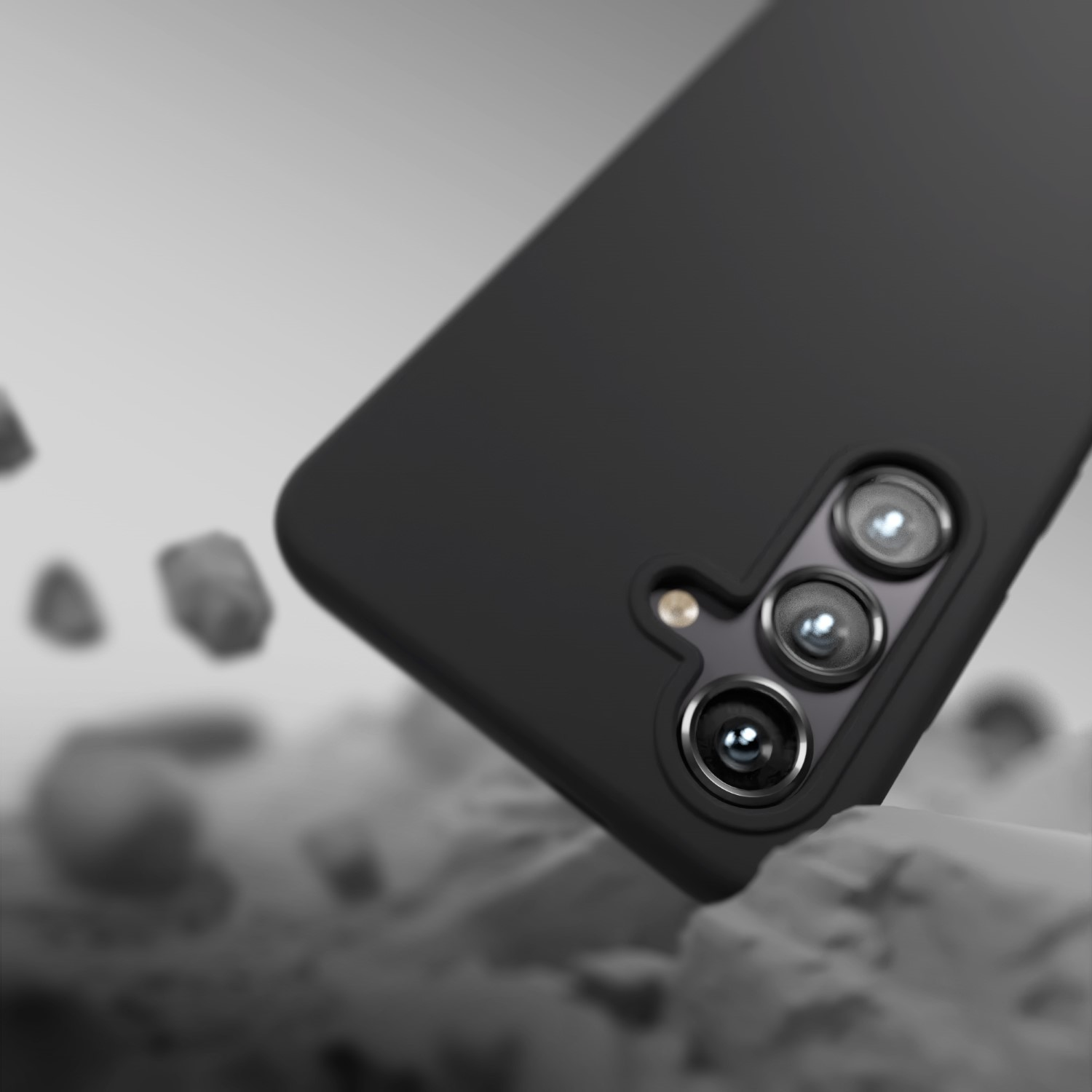 Cover nera per telefono con tre fotocamere che cadono su un paesaggio roccioso.
