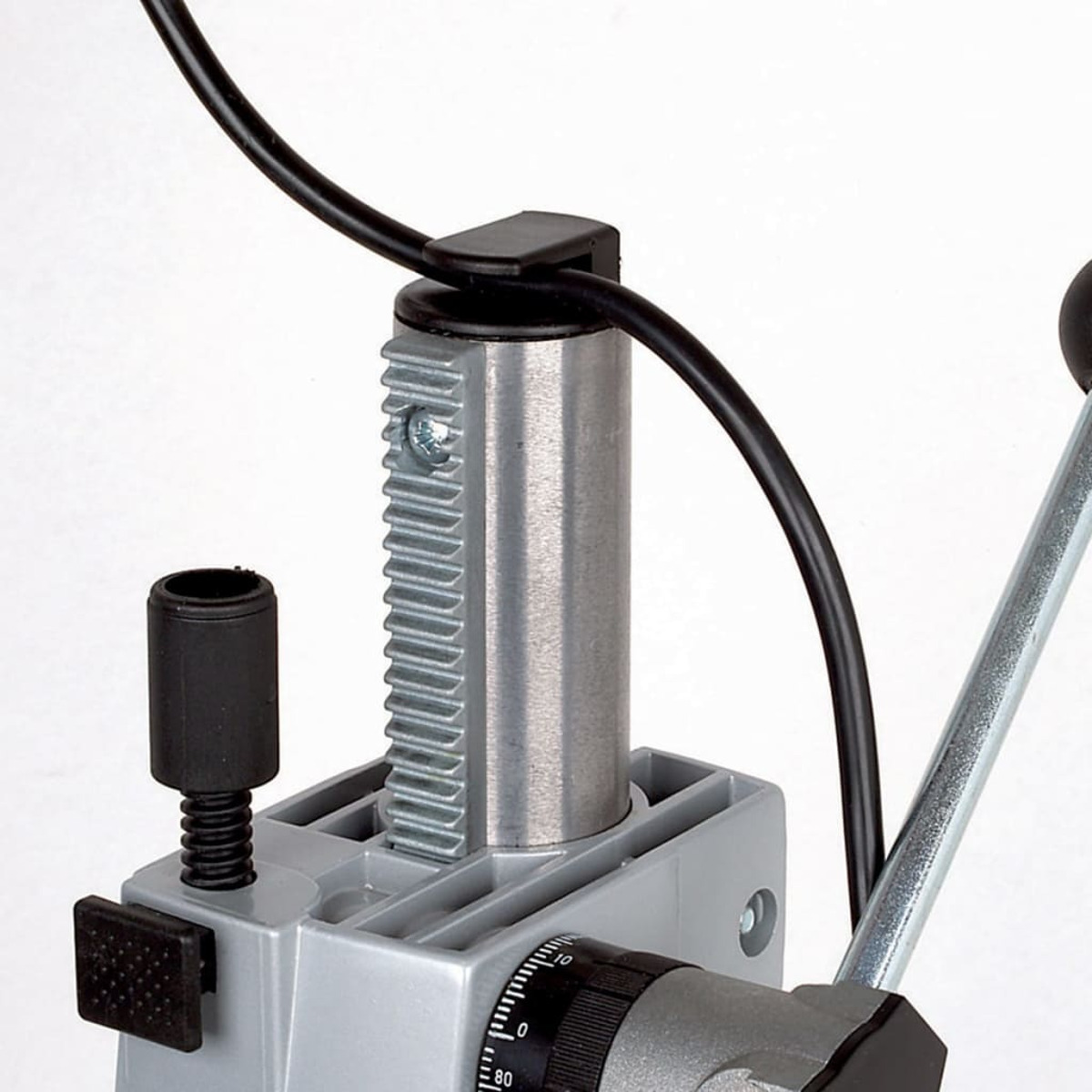 Detailaufnahme einer Bohrmaschine mit Zahnstange, Hebel und schwarzem Kabel.