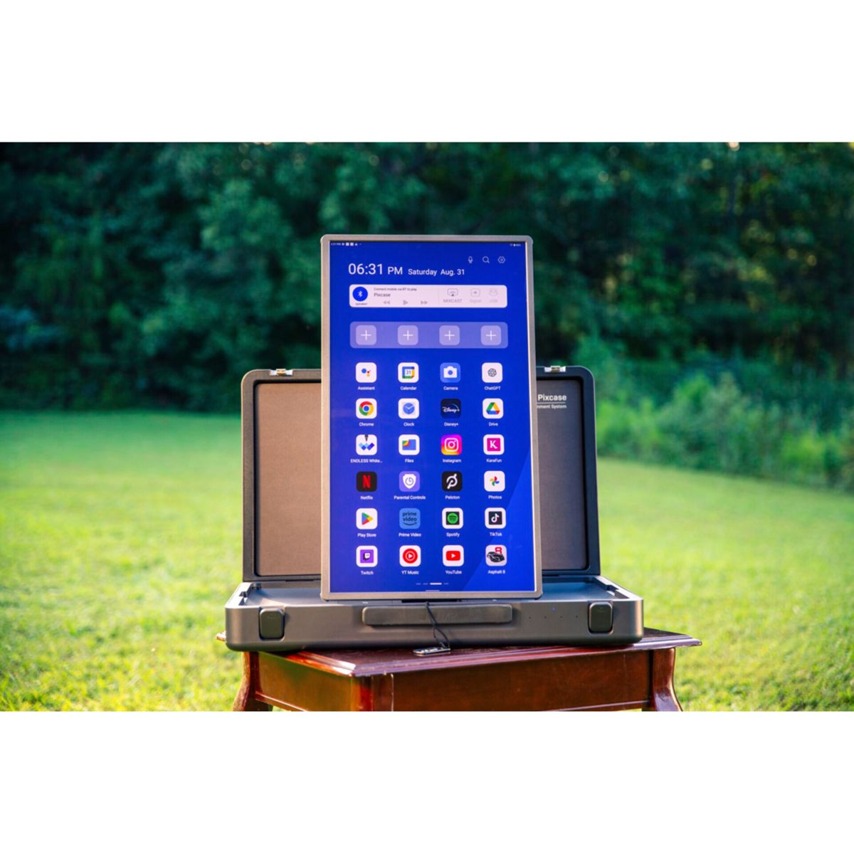Ein Tablet mit vielen Apps steht auf einem Koffer im Freien.