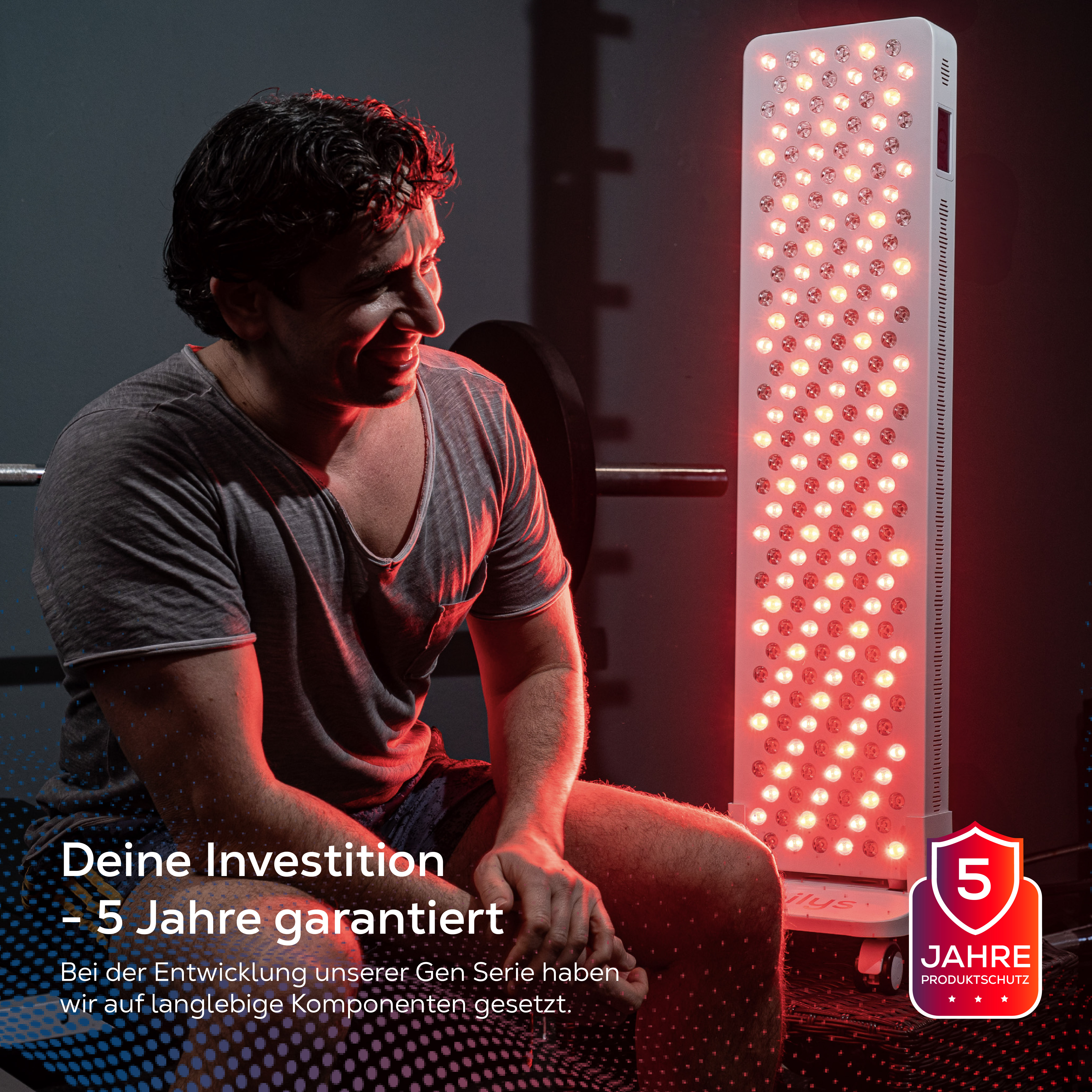 Ein Mann sitzt neben einer roten LED-Therapieplatte in einem Fitnessstudio.