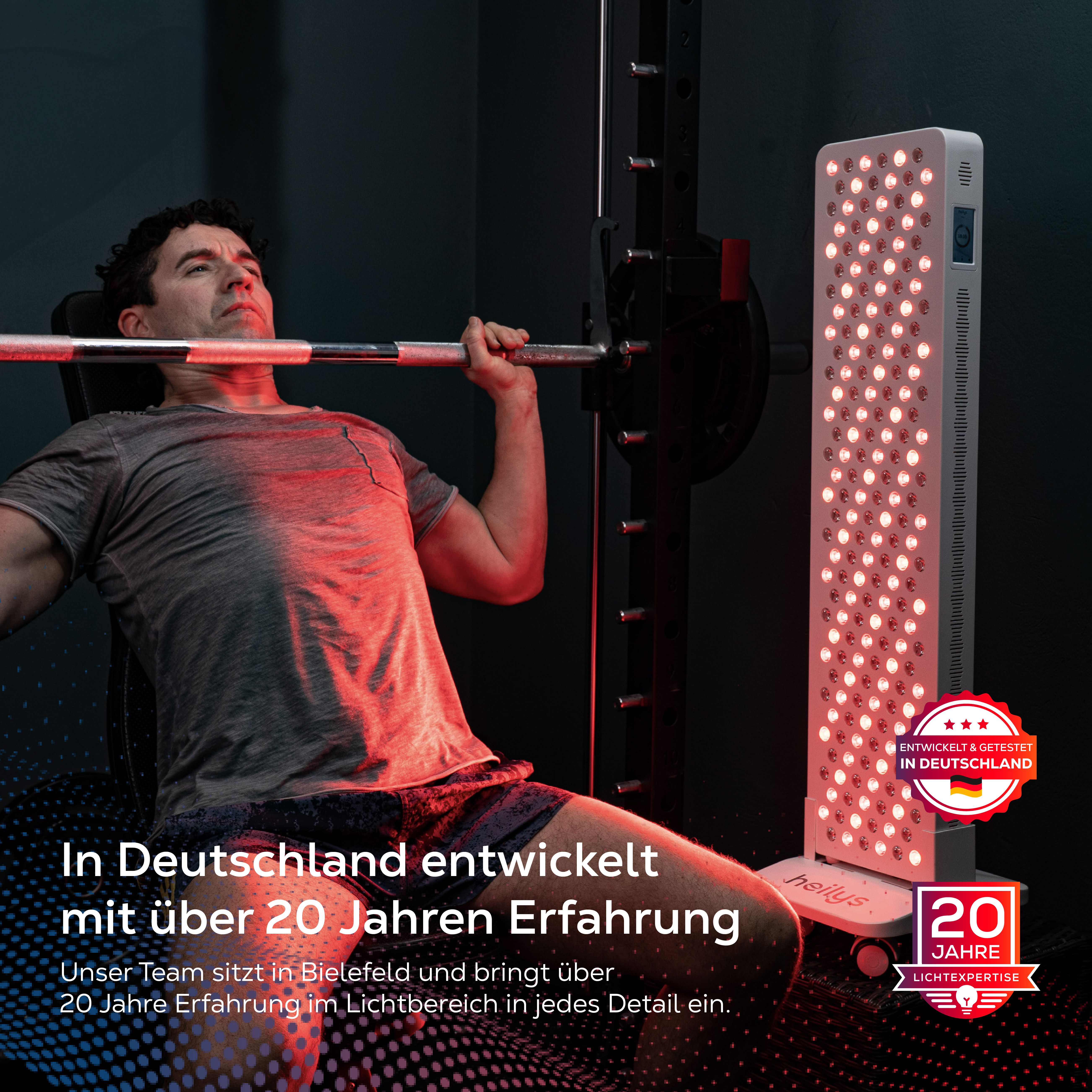 Mann hebt Hantel auf einer Bank, daneben ein Rotlicht-Therapiegerät.