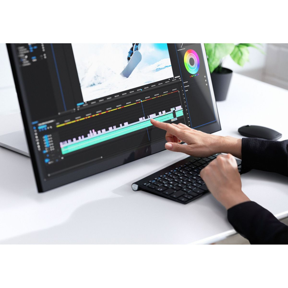 Mani su una tastiera che montano video su un computer con uno snowboarder sullo schermo.