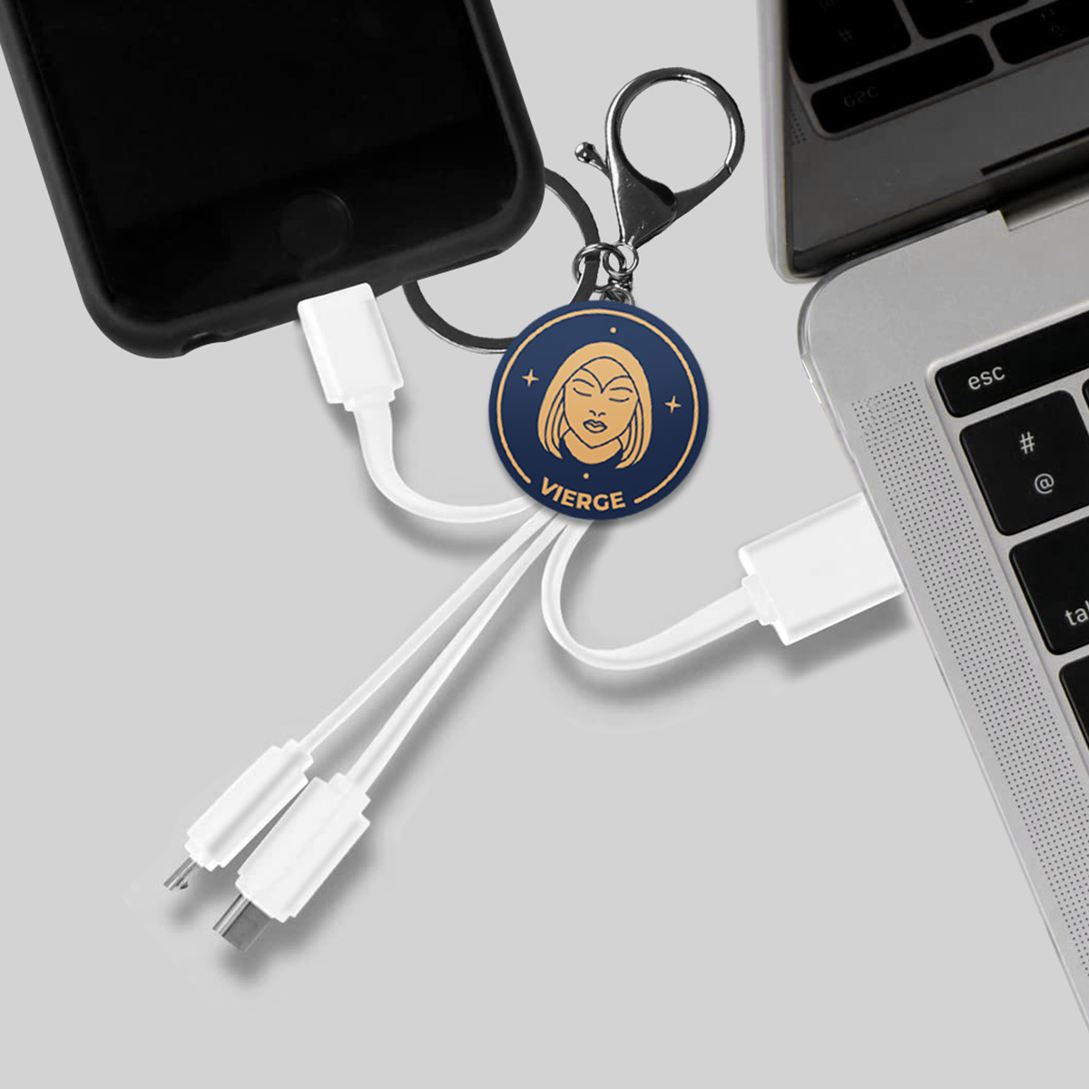 Un telefono, un cavo di ricarica con ciondolo zodiacale e un laptop.