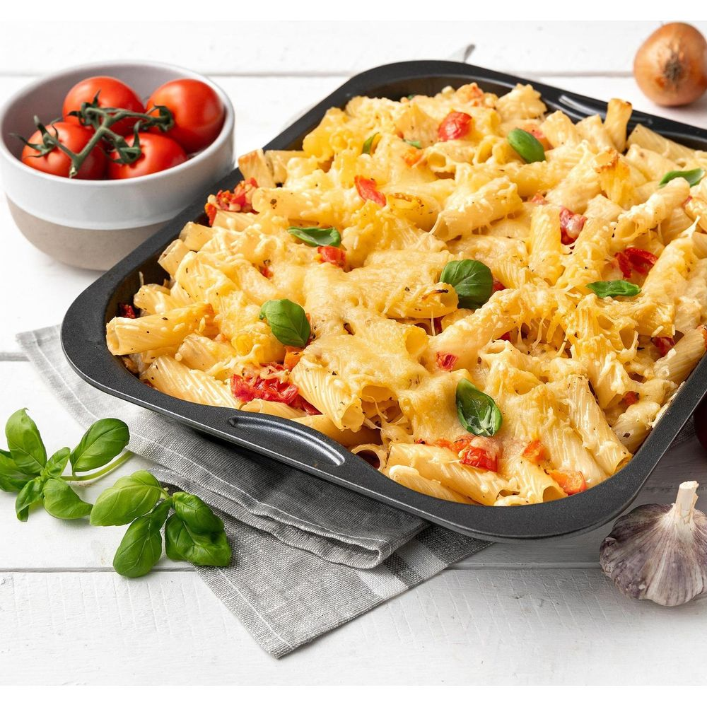Gegrillte Pasta mit Käse, Tomaten und Basilikum in einer Backform.