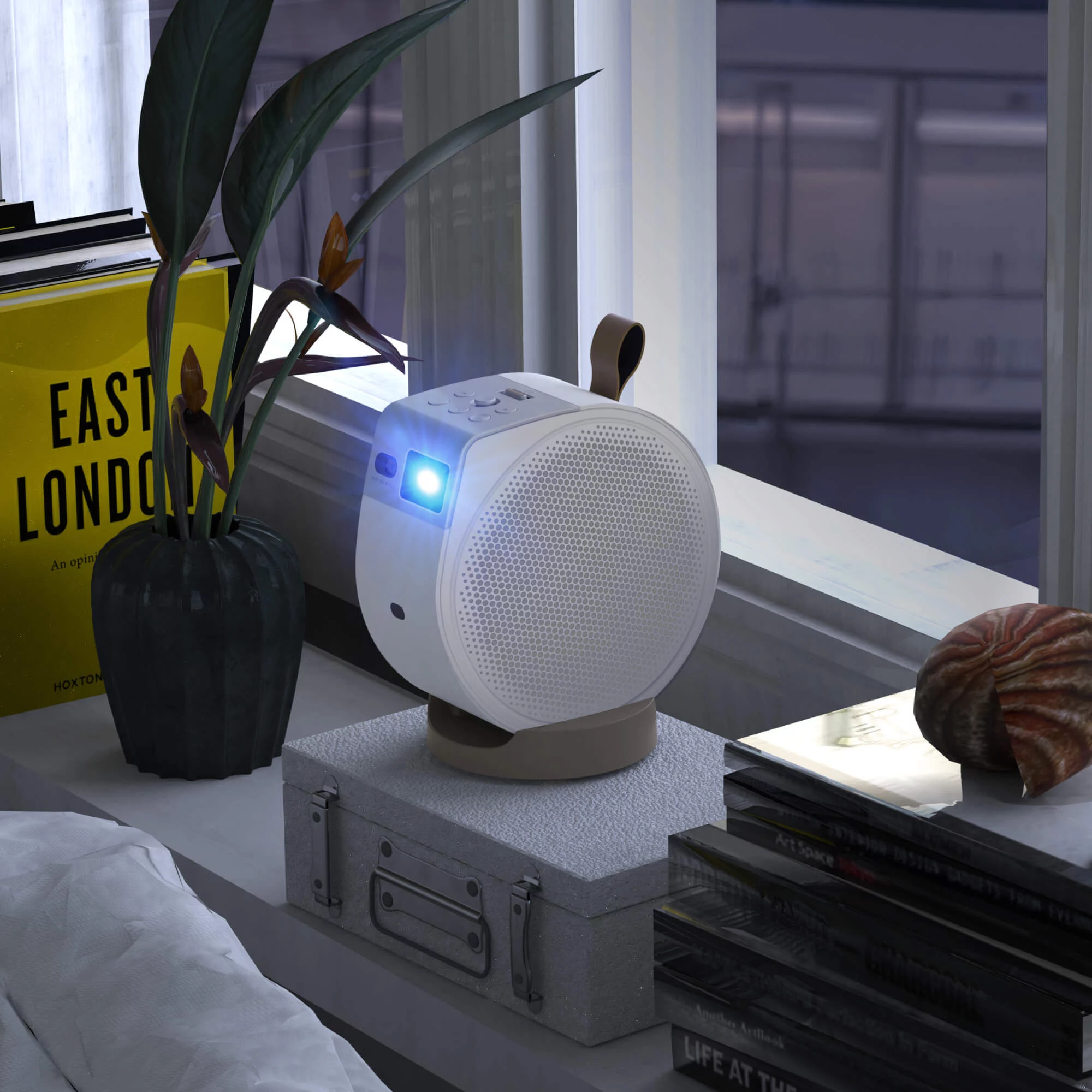 A white projector on a suitcase, with a plant and books beside it.