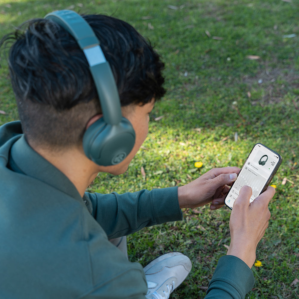 Jeune personne portant des écouteurs à l'extérieur, regardant son smartphone.