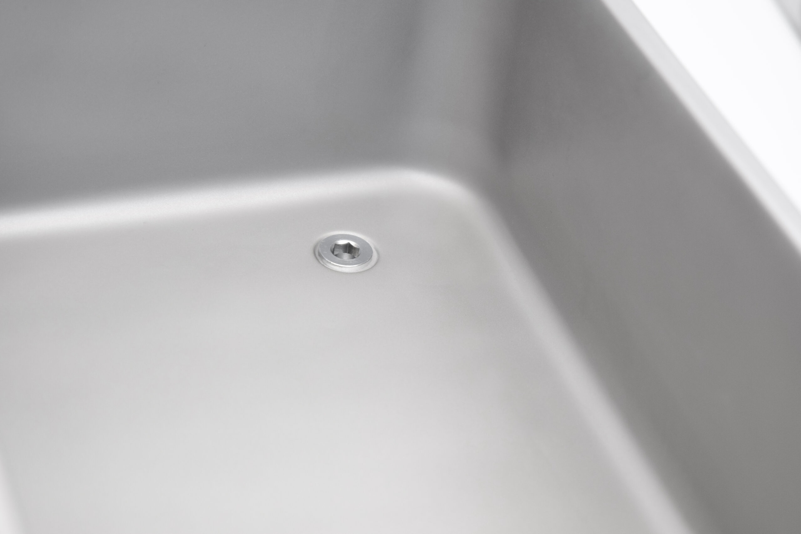 Close-up of a silver sink basin with a drain plug in the center.