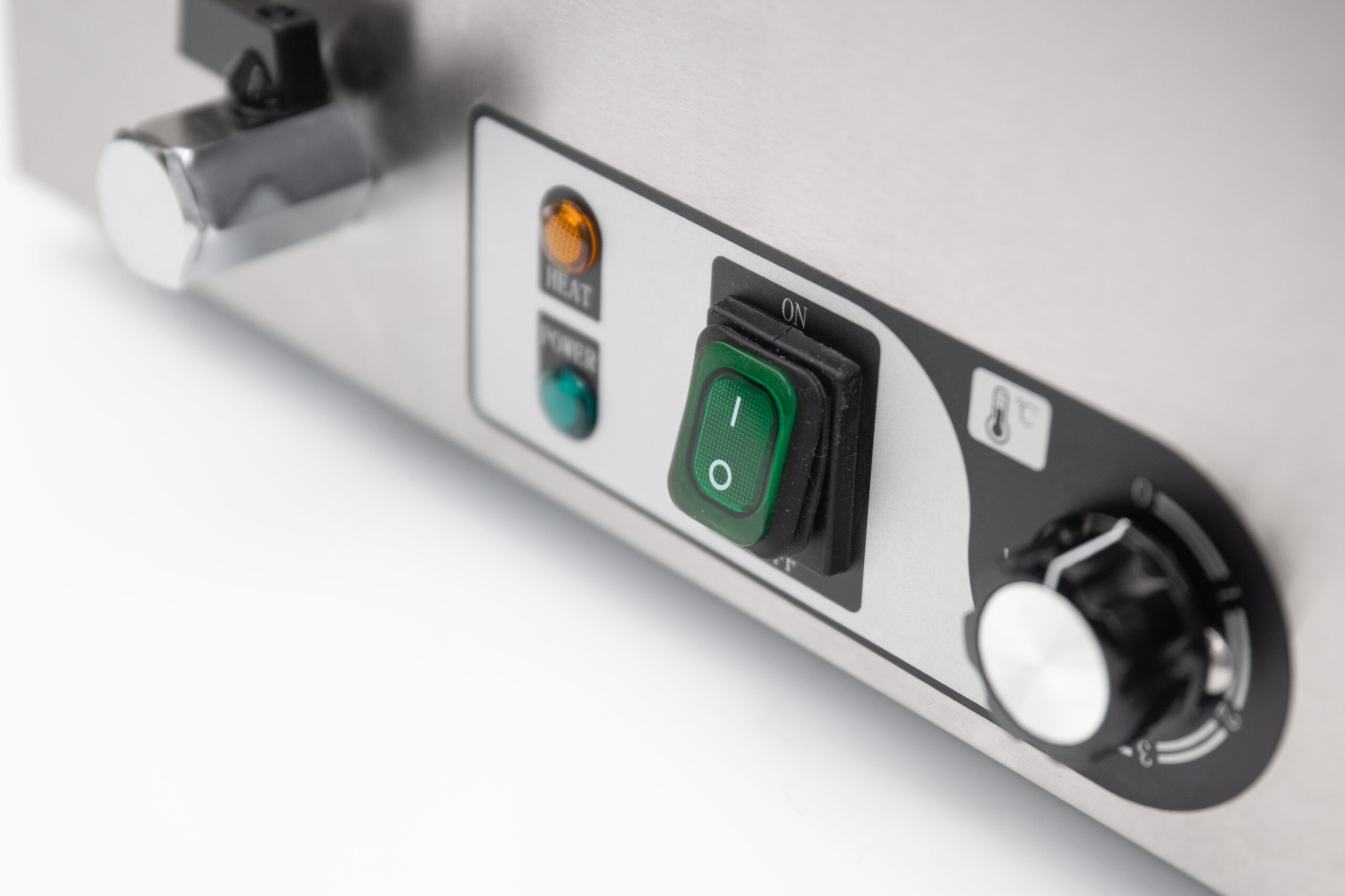 A silver knob, a green on/off switch, and lights on a metal casing.