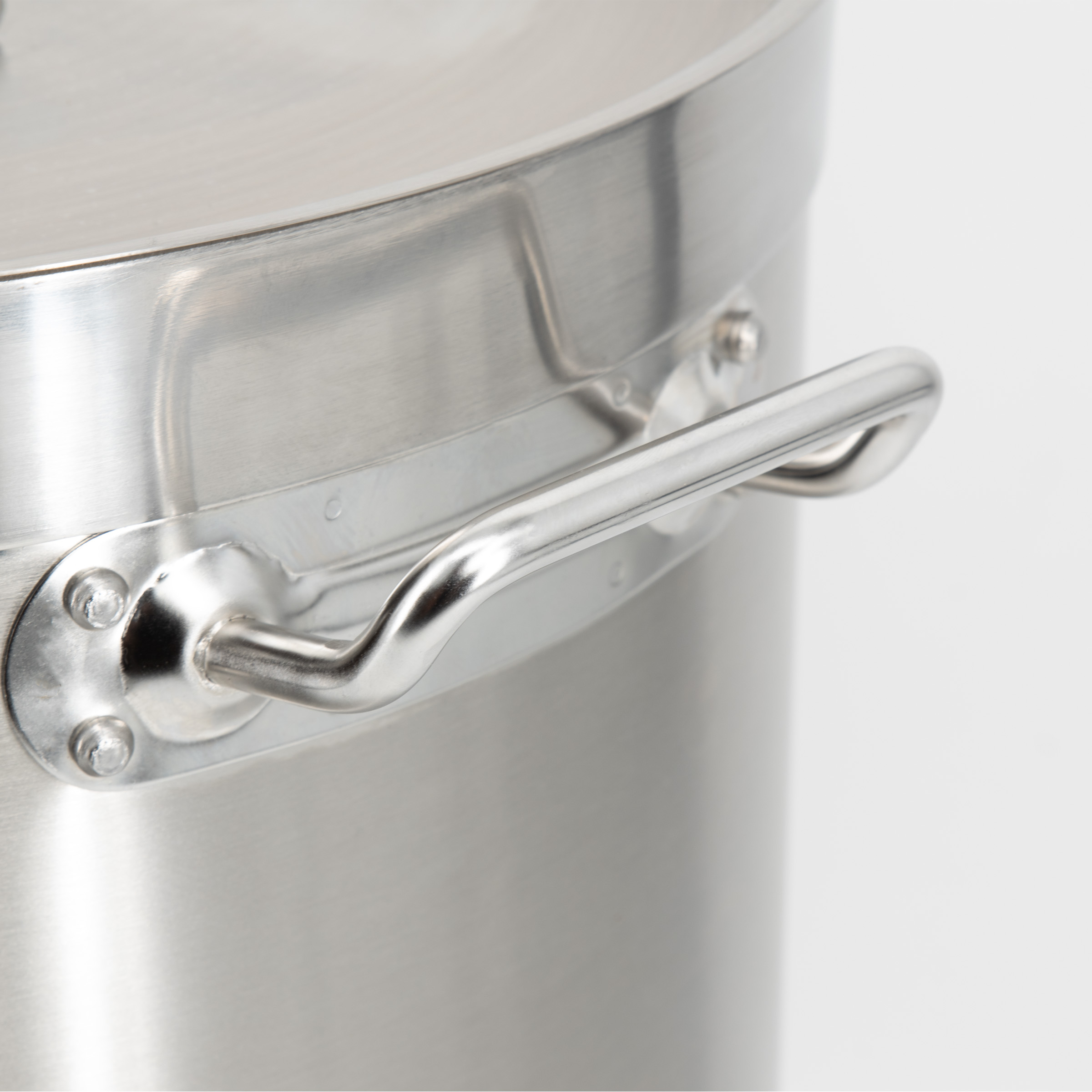 Close-up van de metalen greep van een pan, vastgezet met klinknagels.