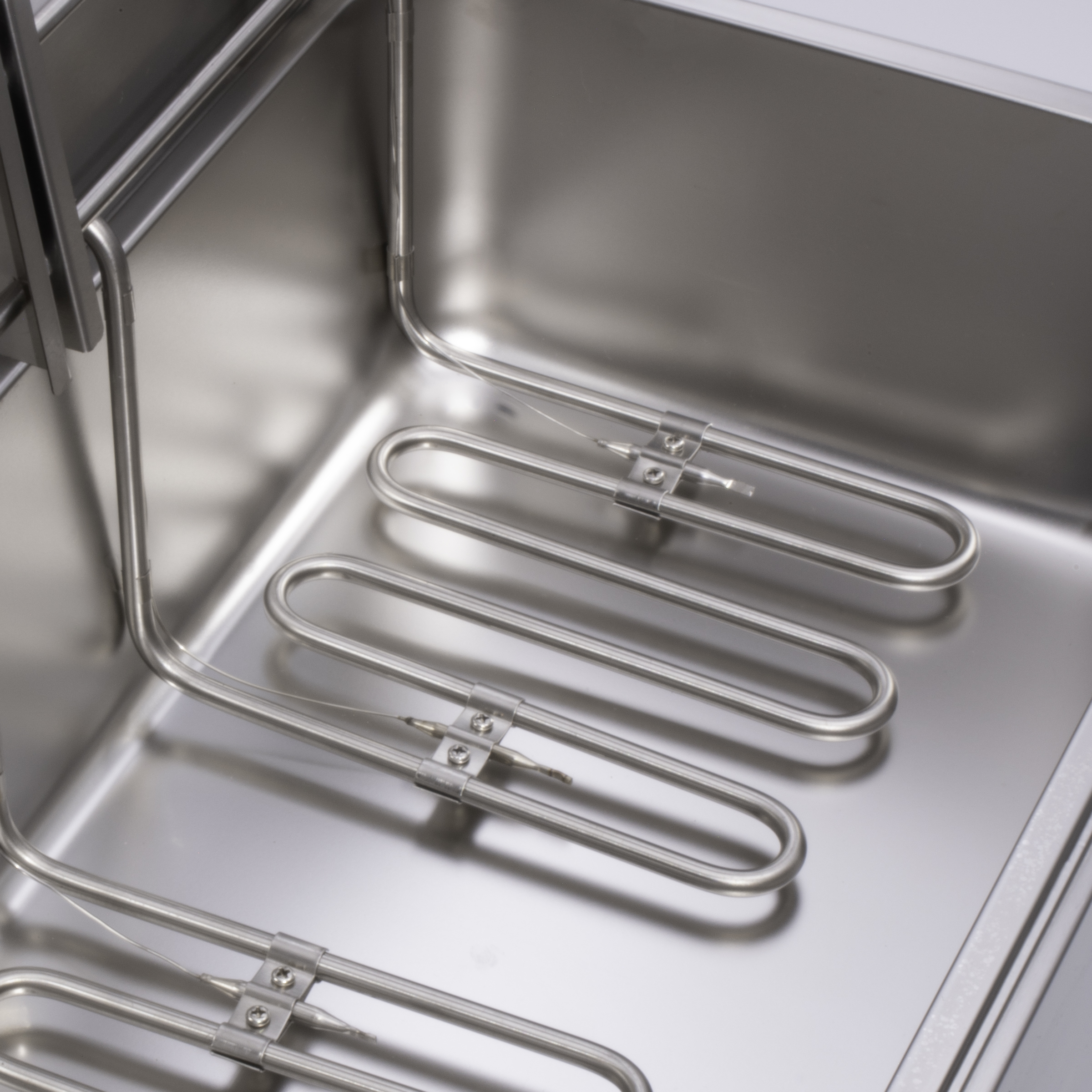 Stainless steel heating elements inside a silver deep fryer basket.