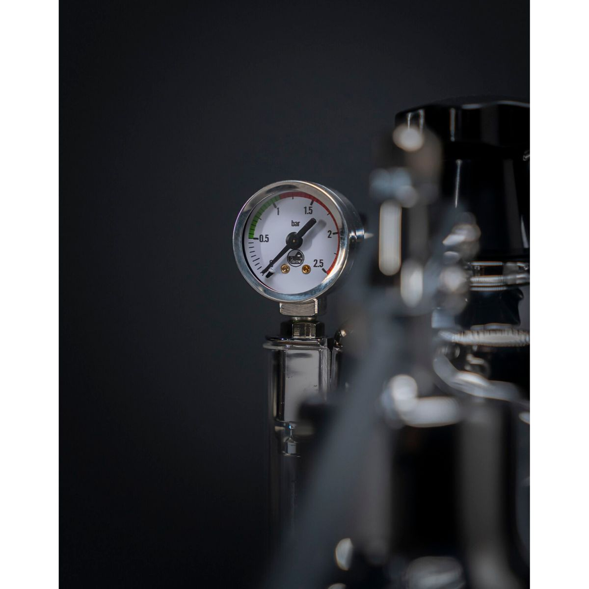 Ein silberner Manometer mit weißem Zifferblatt zeigt Druck in Bar an.