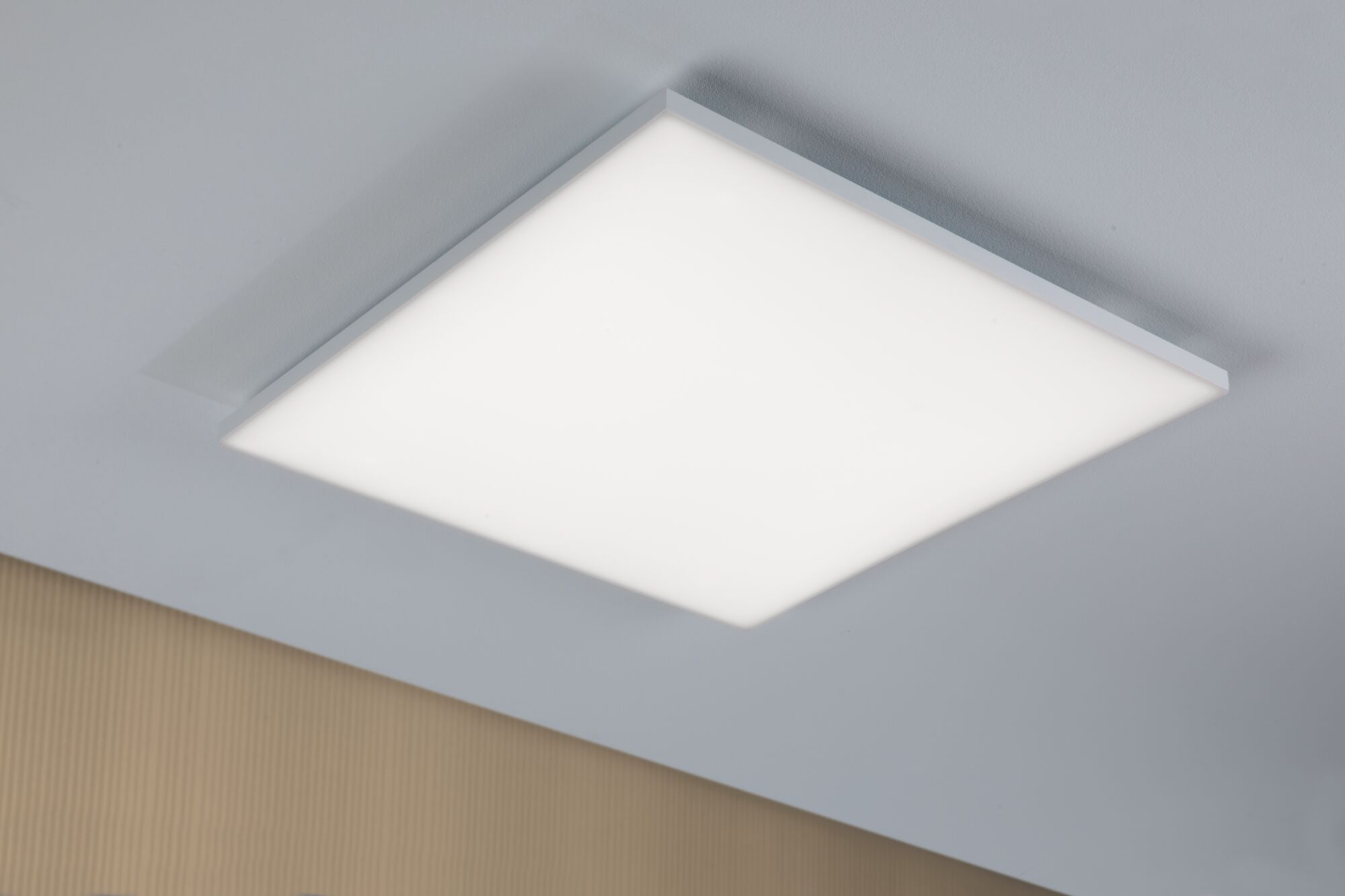 Ein quadratisches Deckenlichtpaneel mit weißem Rahmen hängt an einer weißen Decke.