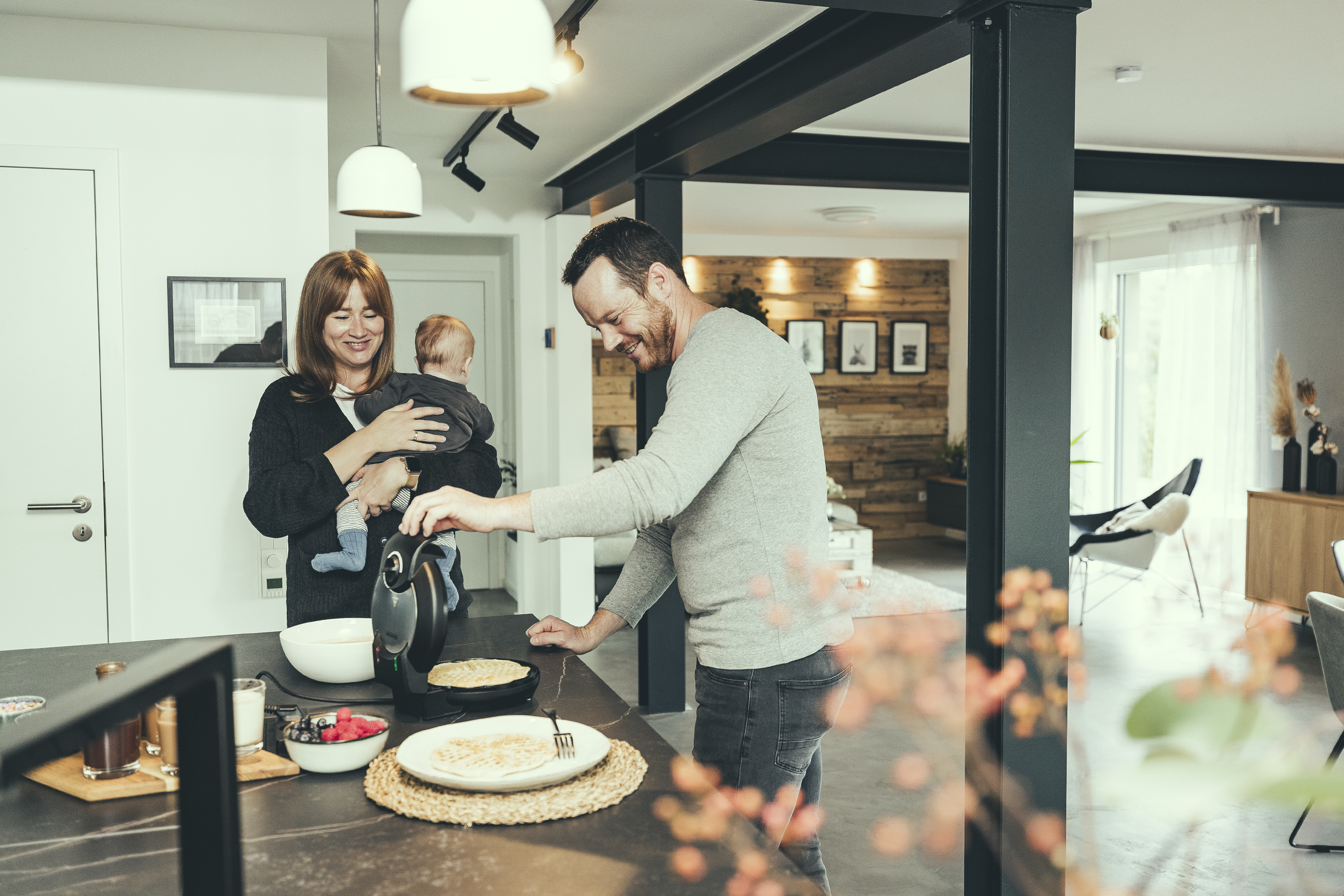 Mężczyzna i kobieta z dzieckiem w kuchni, mężczyzna robi gofry.