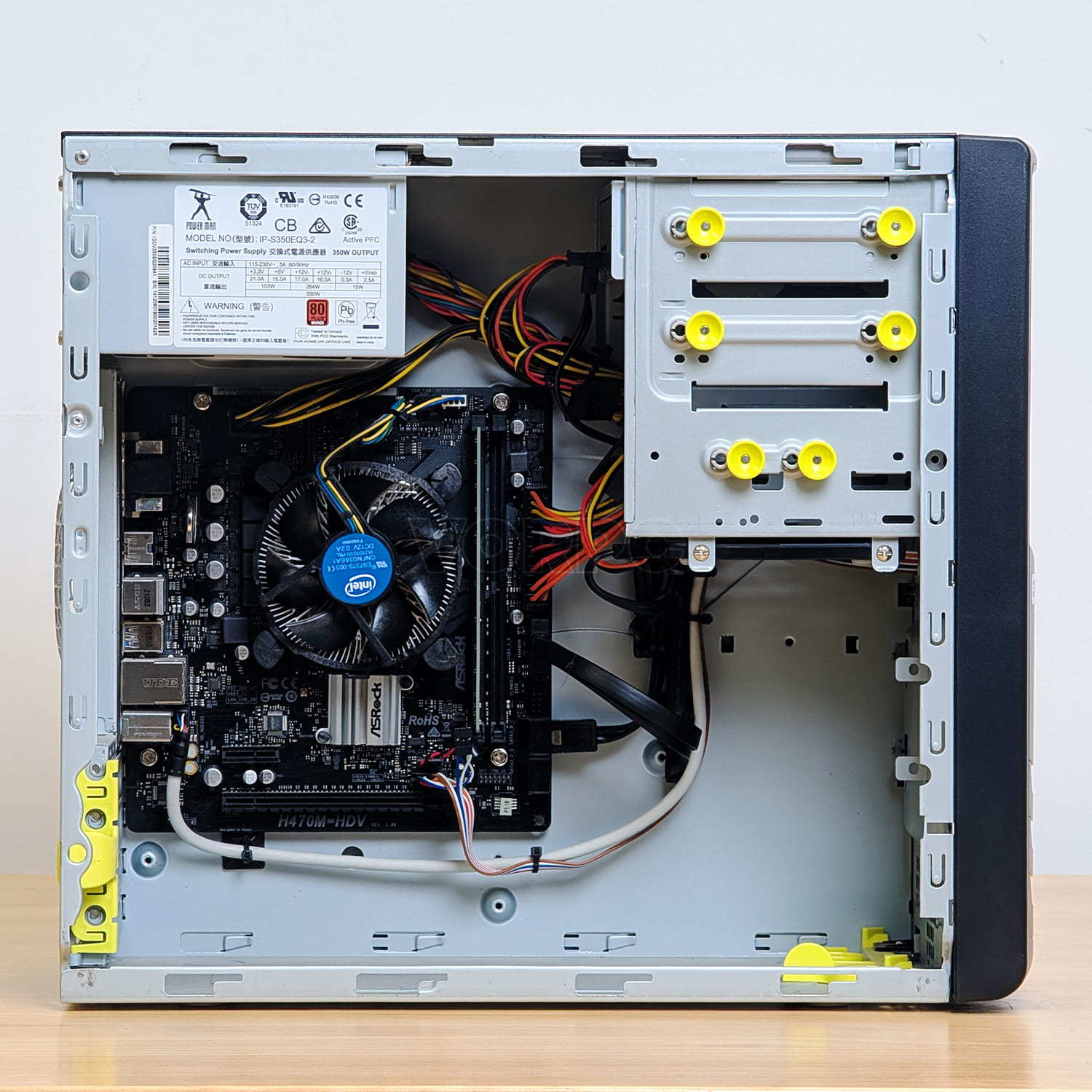 Una torre de computadora abierta muestra la placa base, ventilador de CPU, fuente de alimentación y cables.