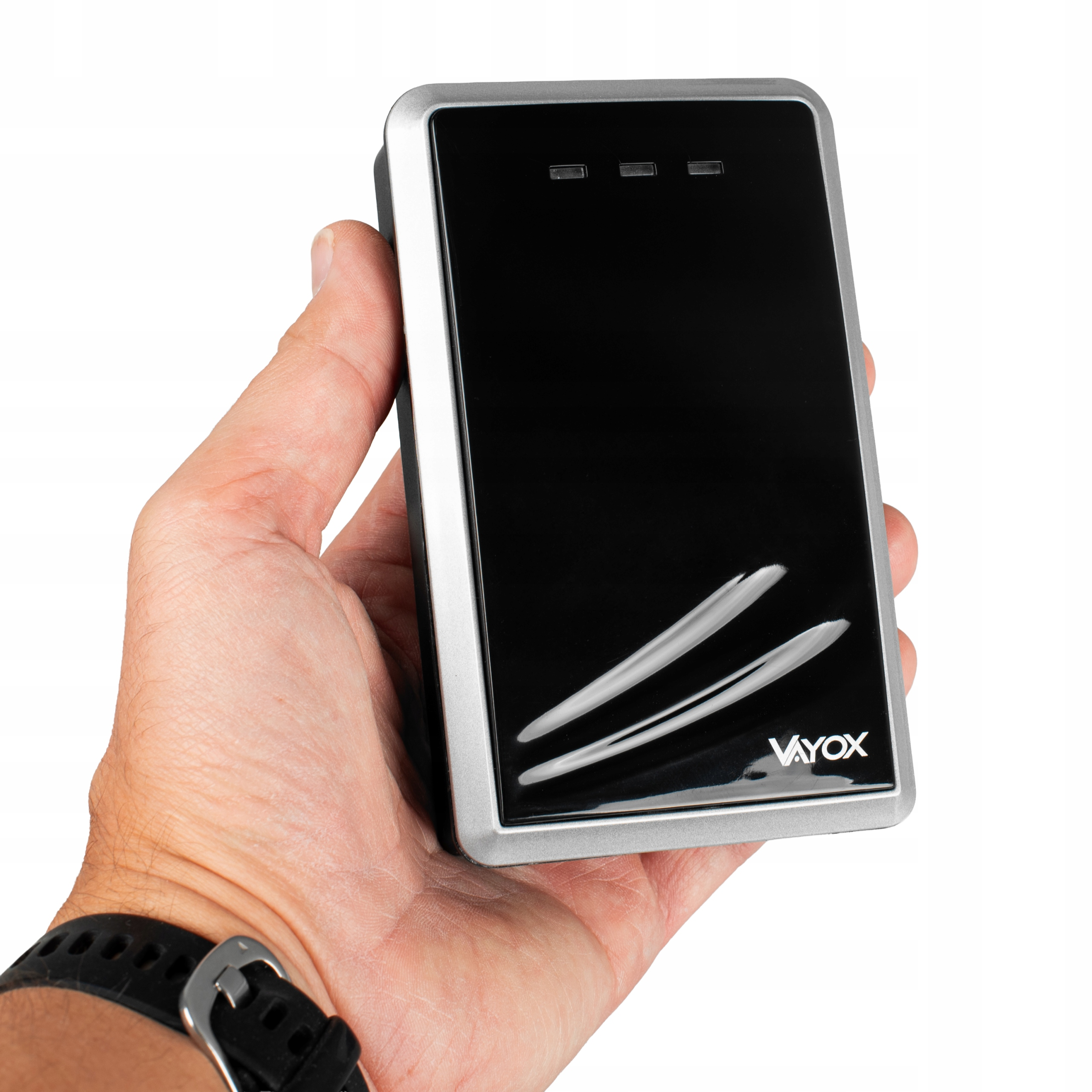 Dłoń trzyma czarne urządzenie Vayox w srebrnej ramce.