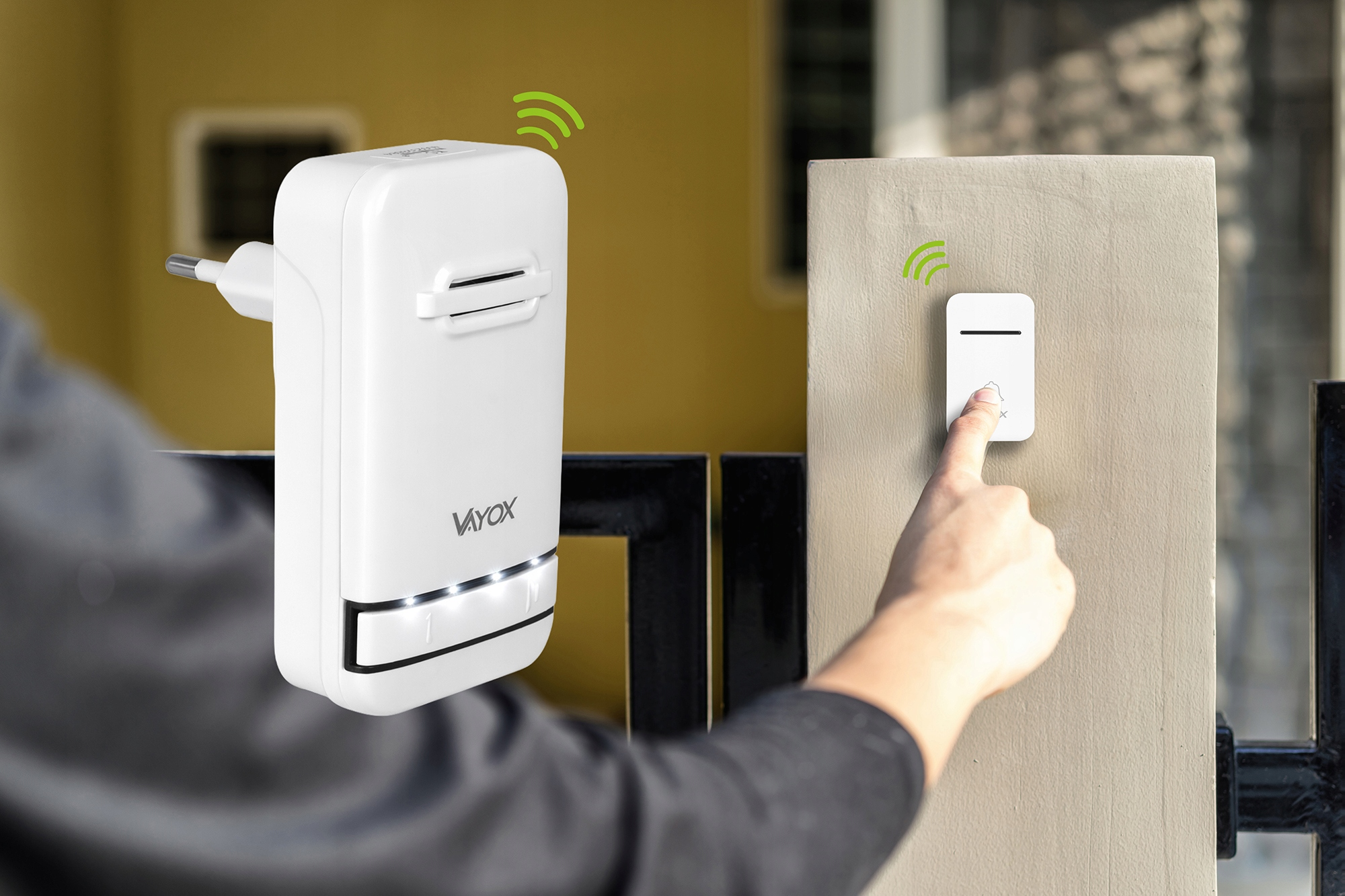 Osoba naciska biały dzwonek do drzwi na ścianie. Białe urządzenie jest na pierwszym planie.