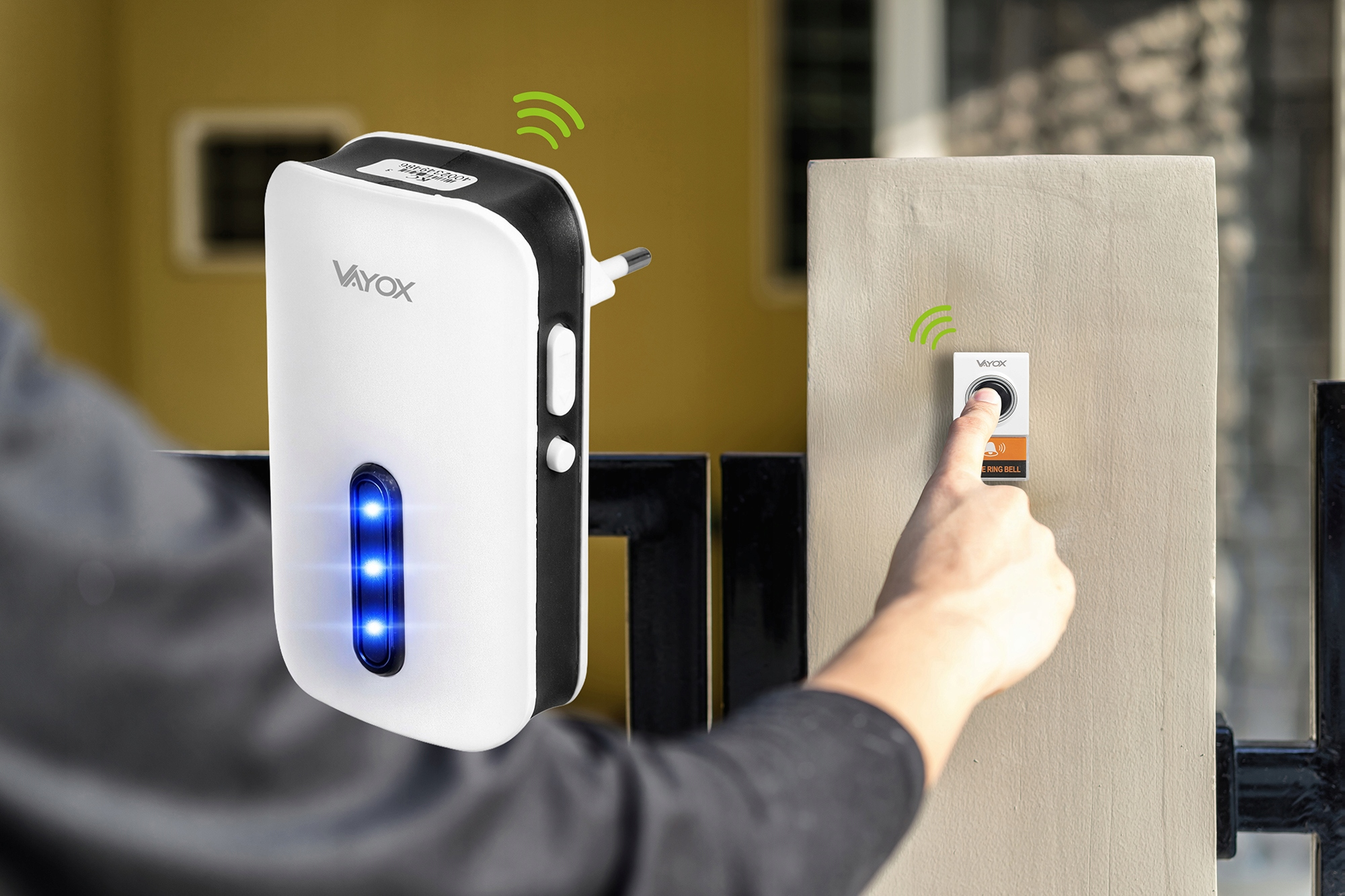 Osoba naciska dzwonek do drzwi. Urządzenie Vayox znajduje się na pierwszym planie.