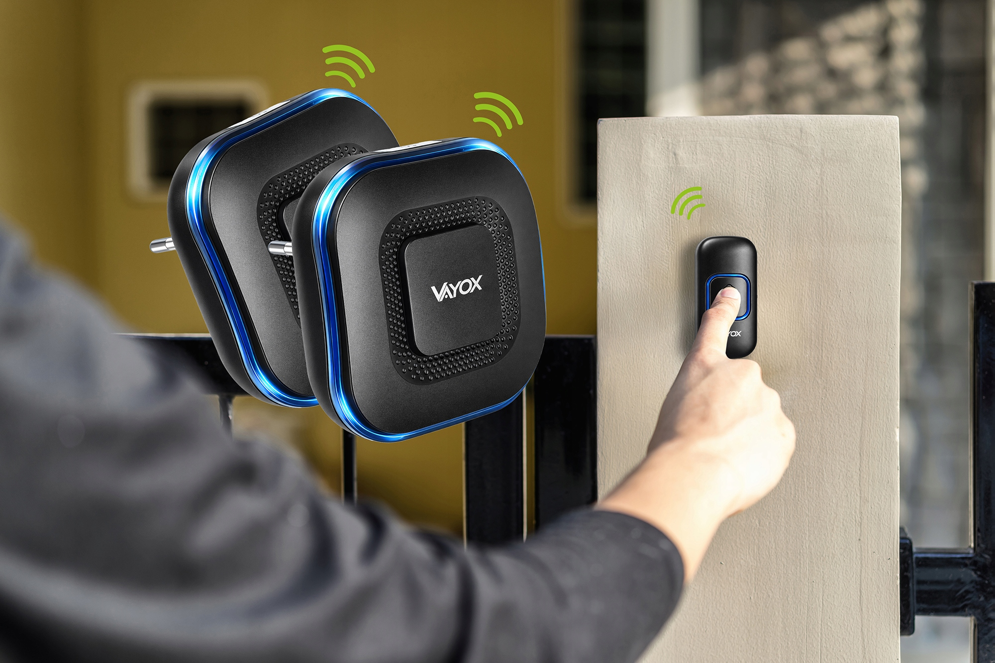 Palec naciska dzwonek; obok znajdują się dwa nadajniki.