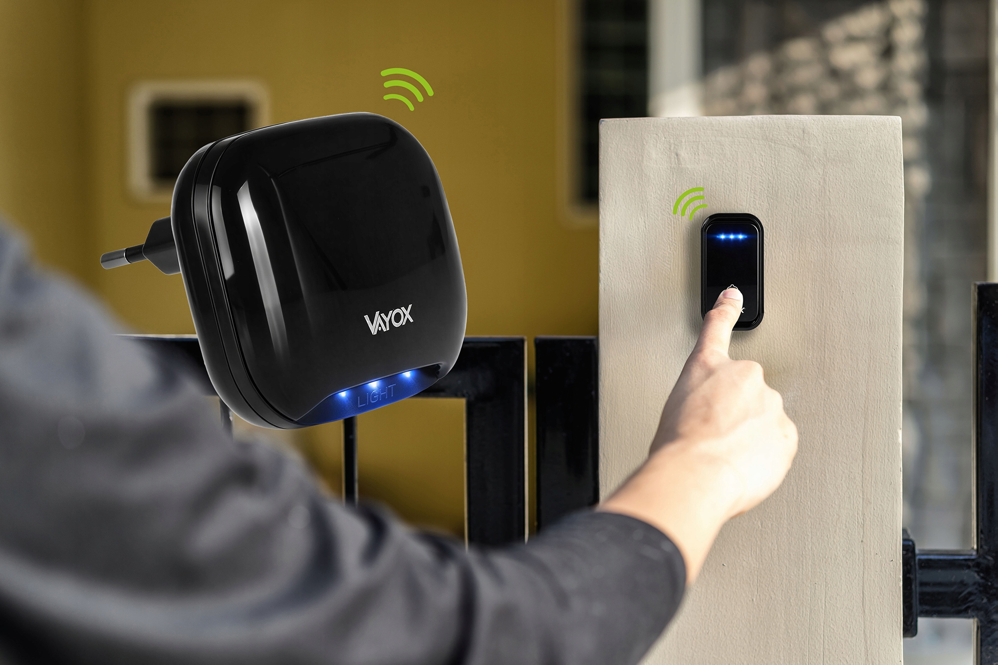 Palec naciska dzwonek; czarna wtyczka ze światłami jest na pierwszym planie.