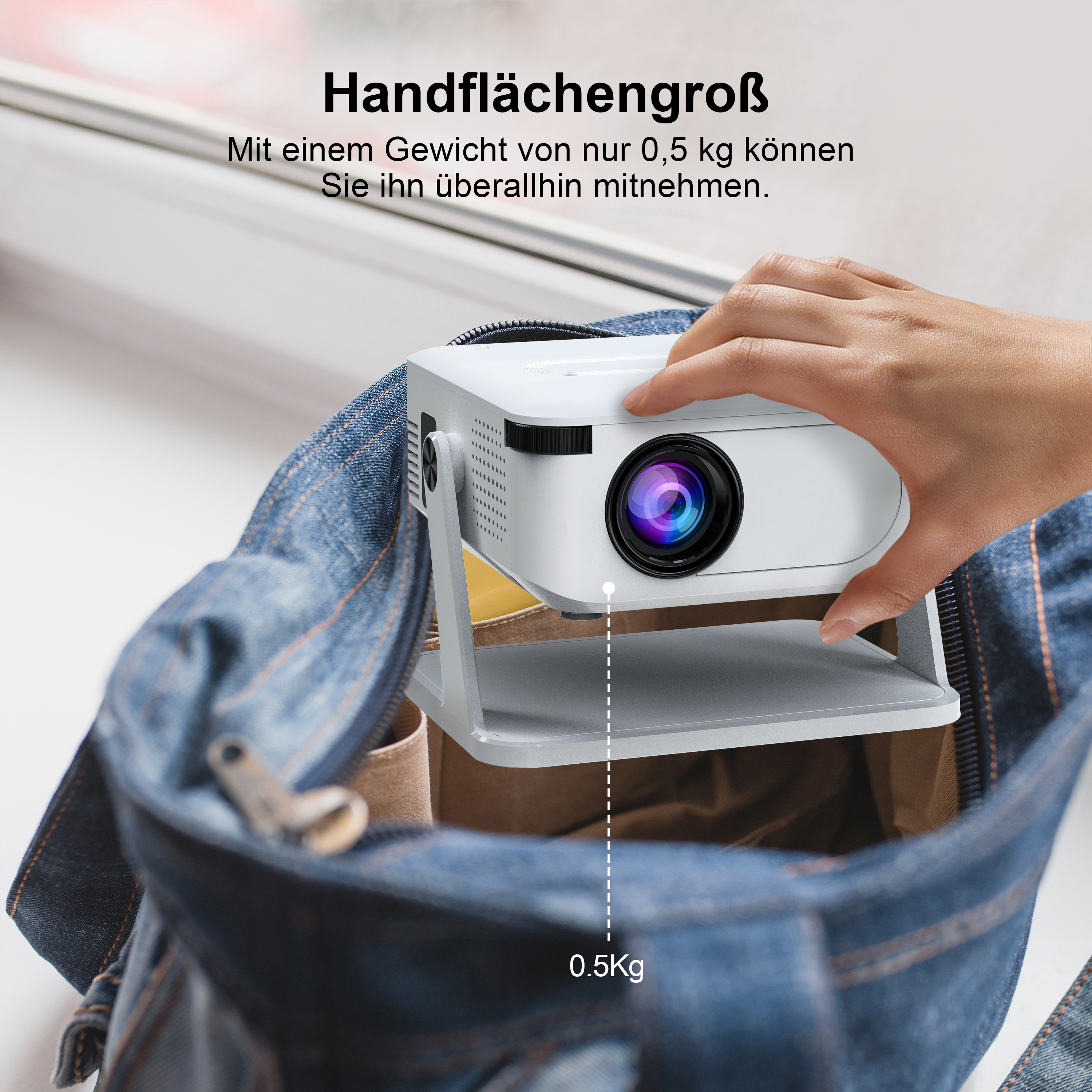 Eine Hand legt einen weißen Projektor in eine Jeanstasche. Er wiegt 0,5 kg.