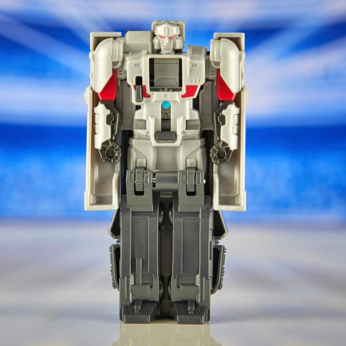 Un robot de juguete gris con detalles rojos se alza sobre fondo azul.
