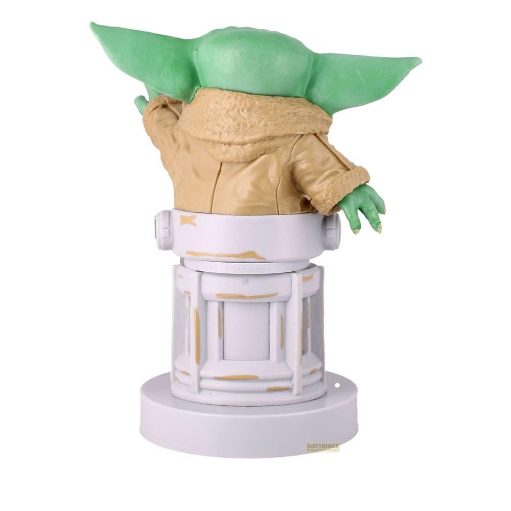 Una creatura verde con grandi orecchie sta su una base, indossa un cappotto.