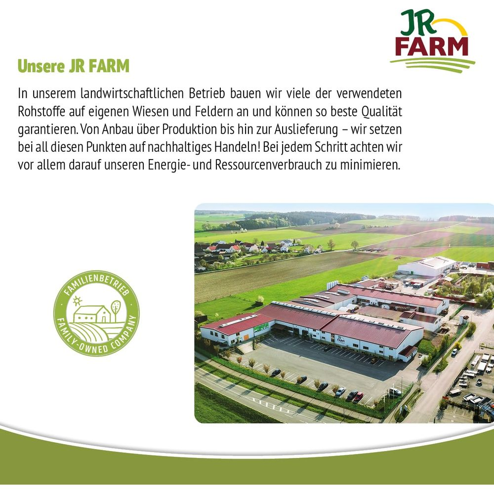 Luftaufnahme eines JR FARM-Betriebs mit Feldern, Gebäuden und einem Dorf im Hintergrund.