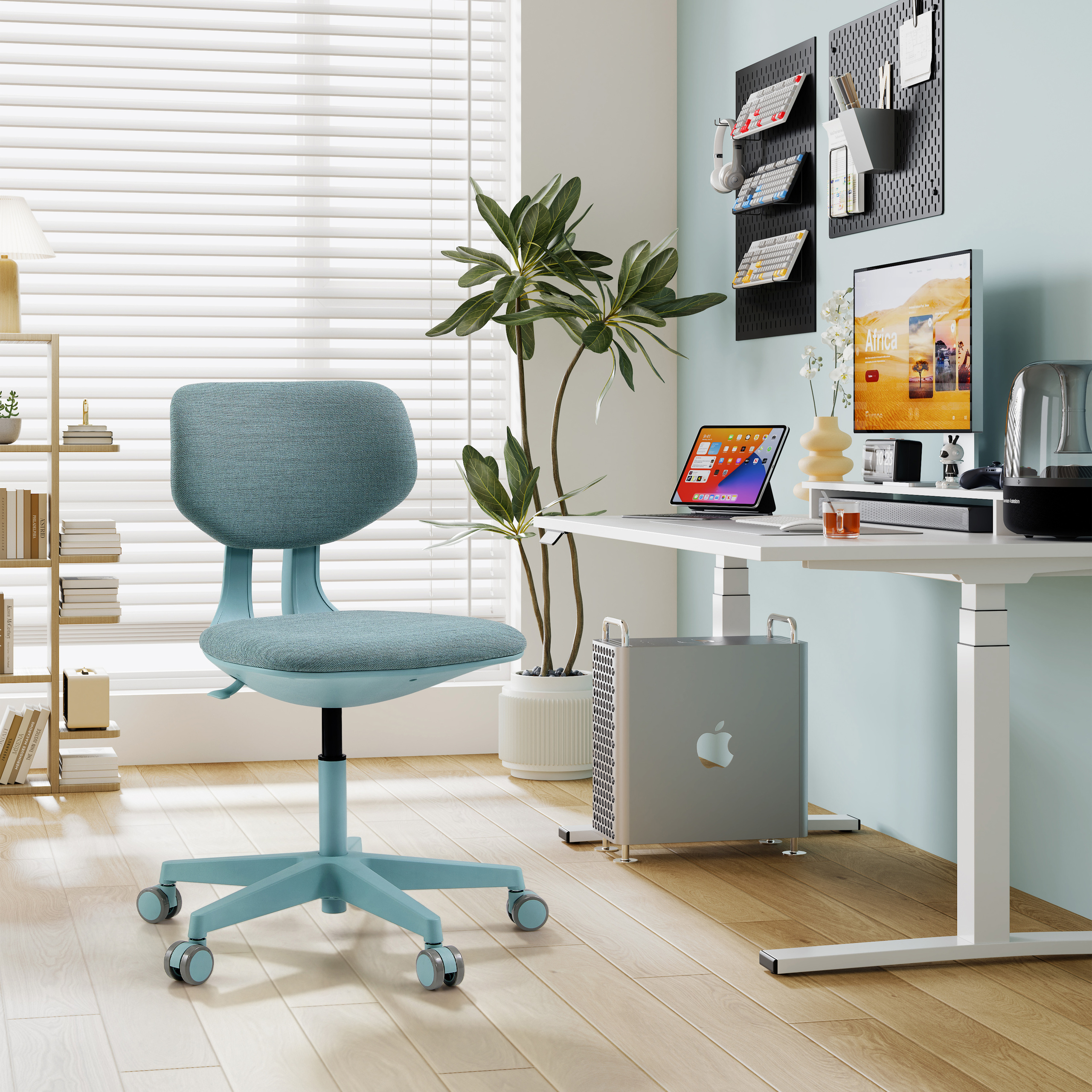 Ein helles Büro mit einem blauen Stuhl, Schreibtisch, Computer und Pflanze.