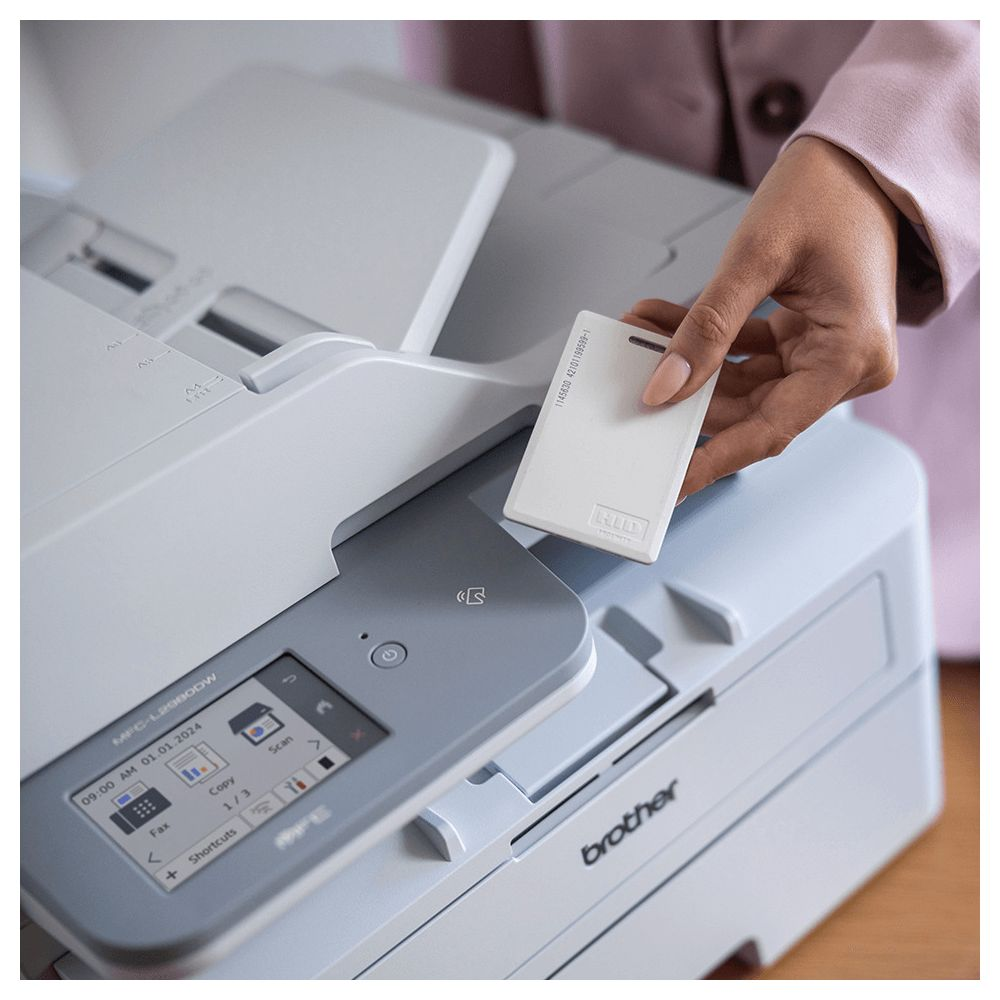 Une main tient une carte RFID blanche au-dessus d'une imprimante Brother.