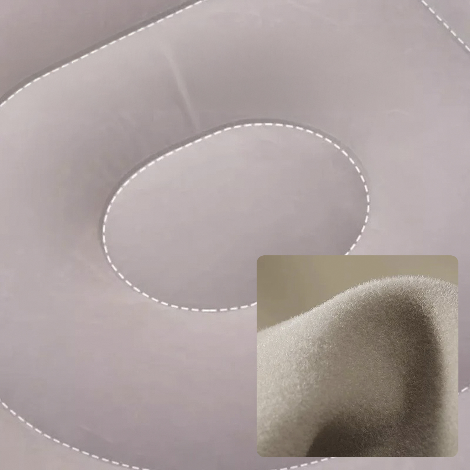 Primo piano di una superficie in tessuto grigio con cuciture bianche e un inserto di tessuto soffice.