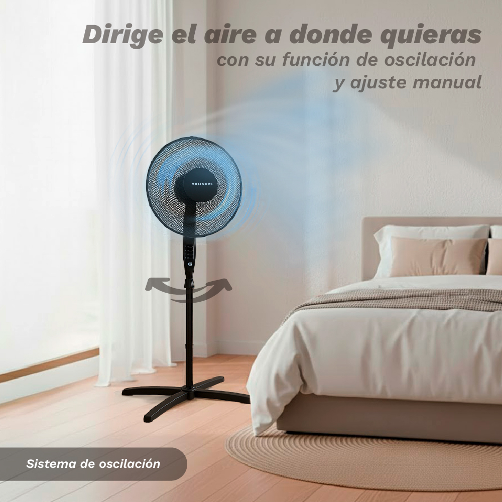 Un ventilador de pie negro oscila en un dormitorio junto a una cama.