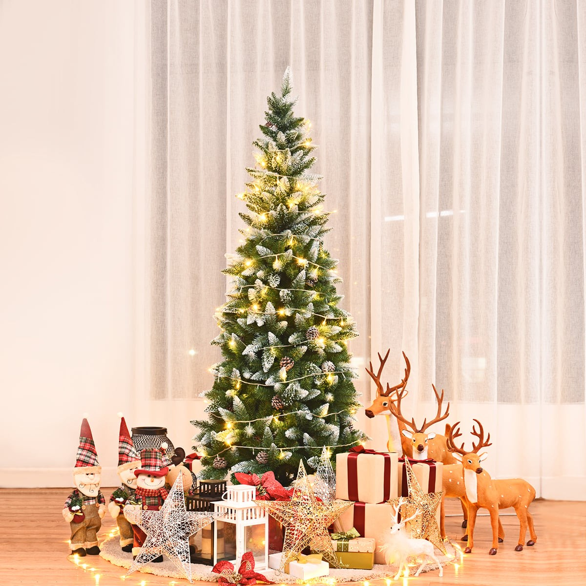 Een versierde kerstboom met lampjes, cadeaus, rendierfiguren en kerstman decoraties.