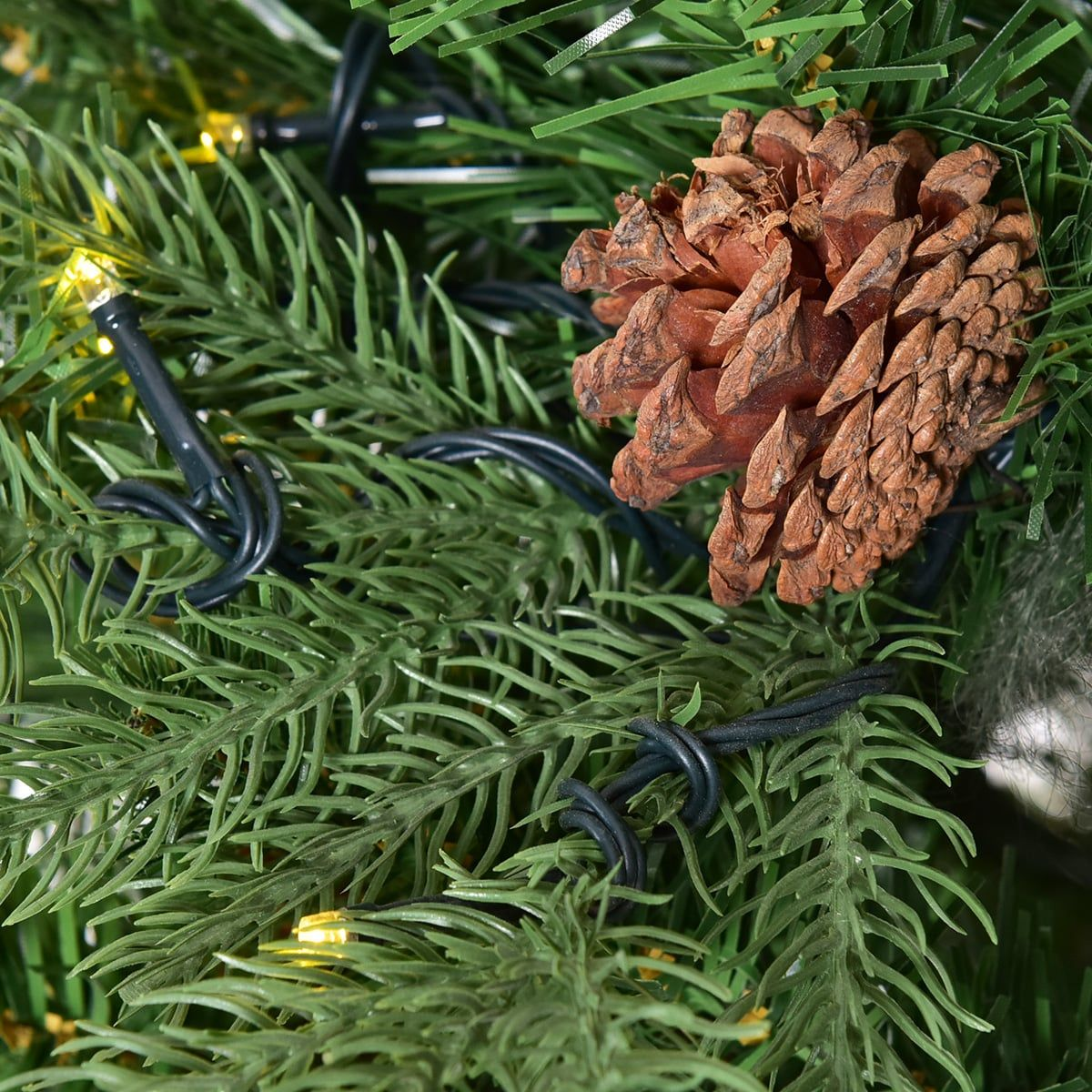 Een dennenappel en lampjes op een kerstboom.