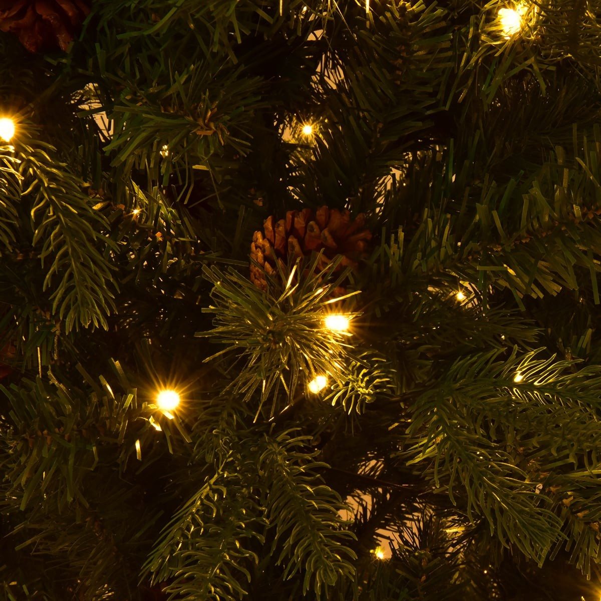 Close-up van een kerstboom met dennenappels en lampjes.