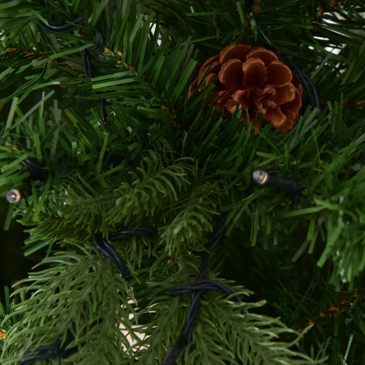 Een dennenappel en lampjes op een kerstboom.
