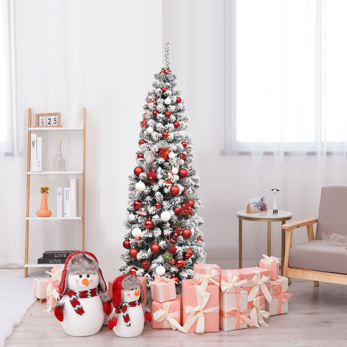 Een bevlokte kerstboom met rode en witte ornamenten, twee sneeuwpoppen en roze geschenkdozen.