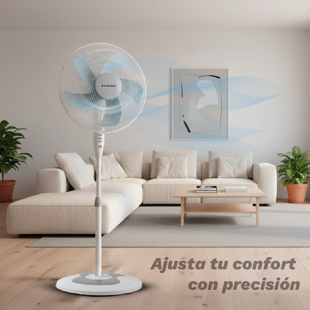 Un ventilador de pedestal blanco en una sala de estar con sofá y mesa de centro.