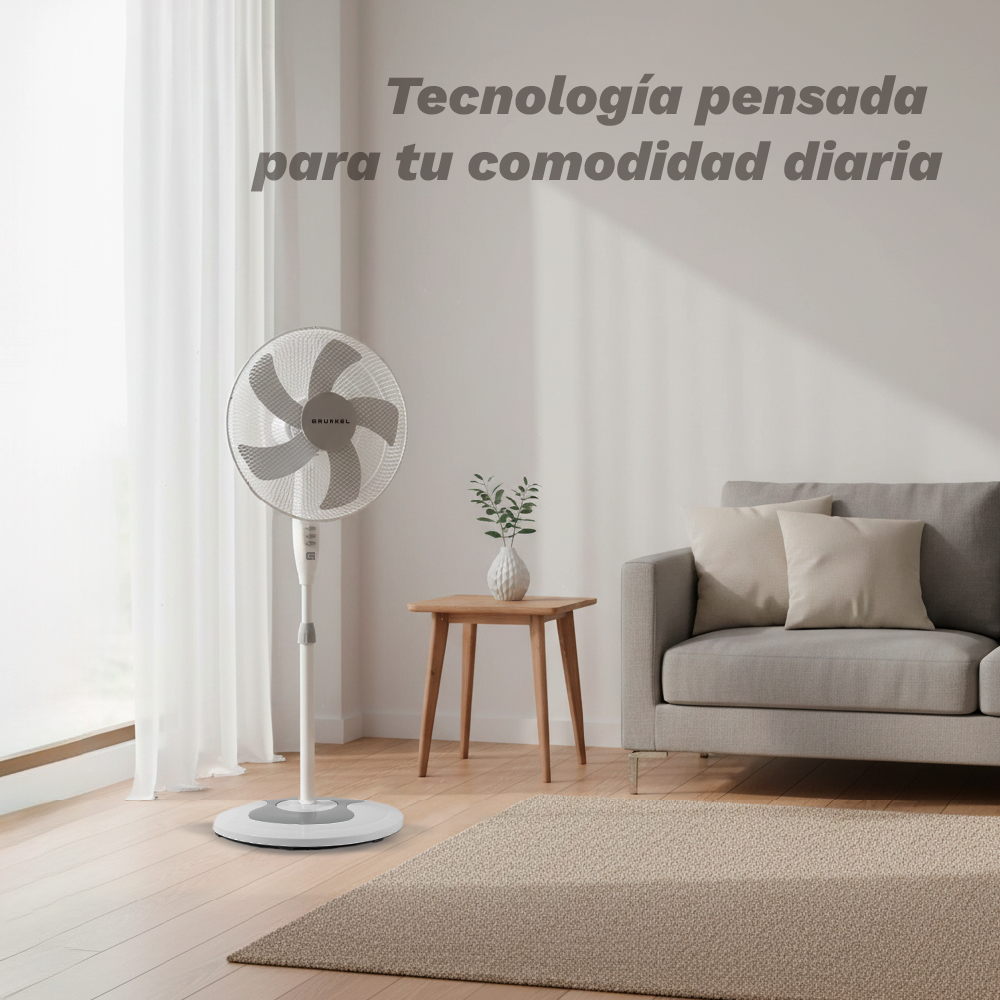 Un ventilador de pie blanco está junto a un sofá en una habitación luminosa.