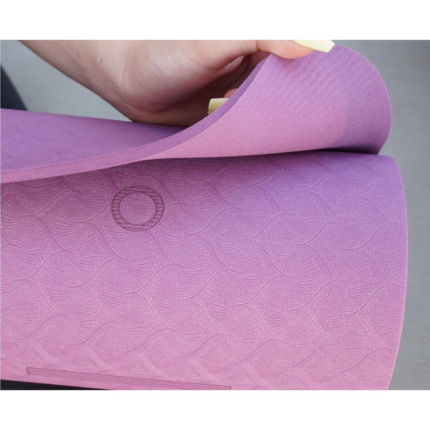 Een hand buigt een paarse yogamat met patroon.