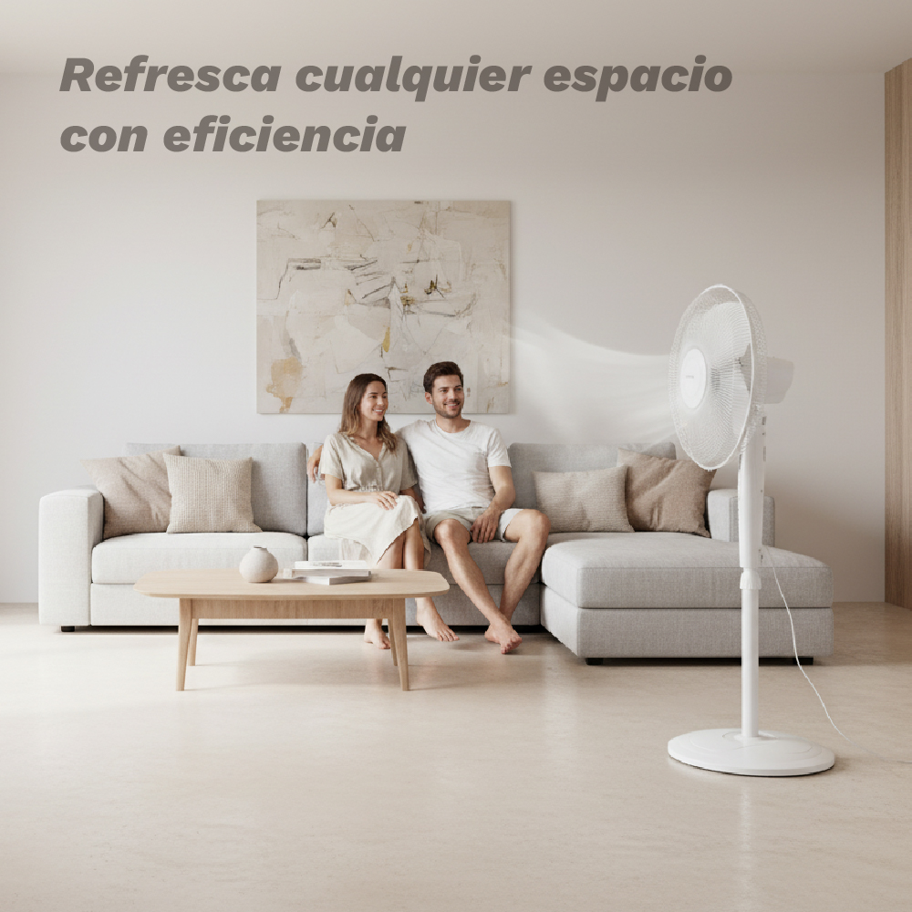 Una pareja sentada en un sofá mientras un ventilador funciona al frente.