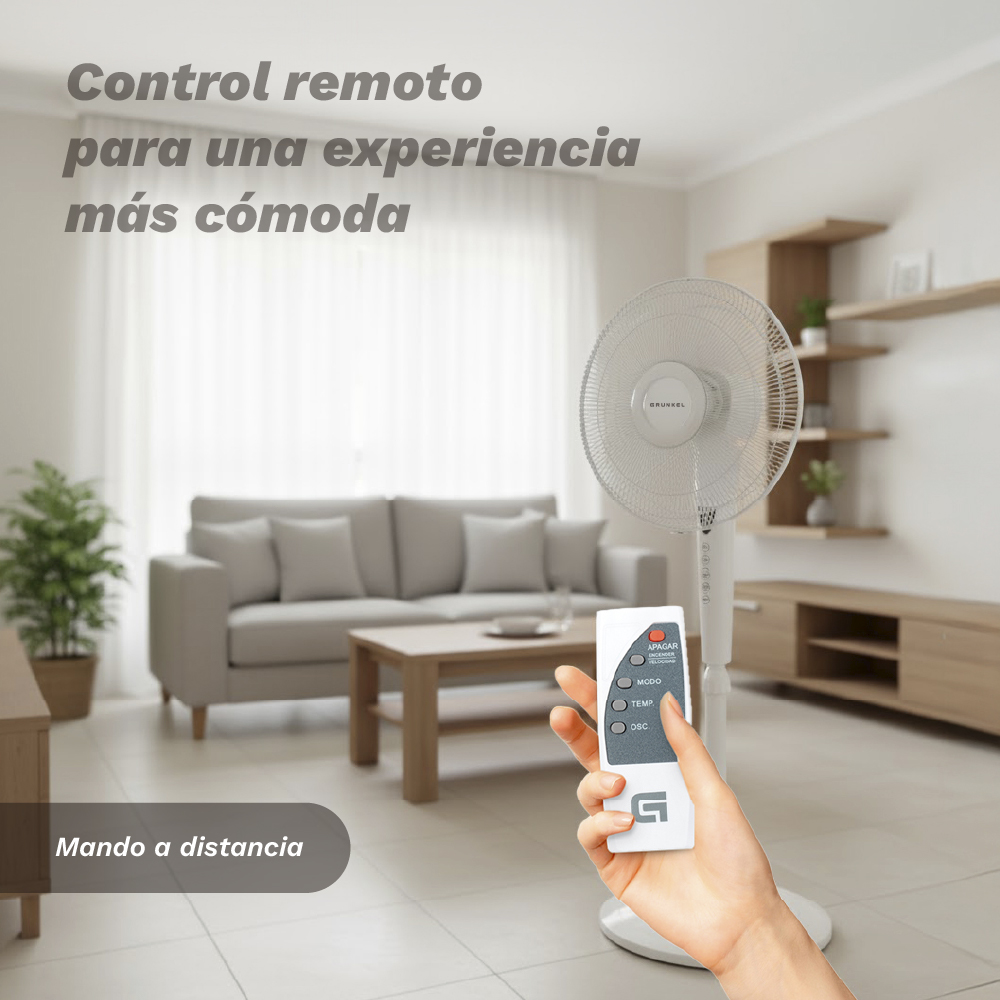 Una mano sostiene un mando a distancia para un ventilador de pie en un salón.