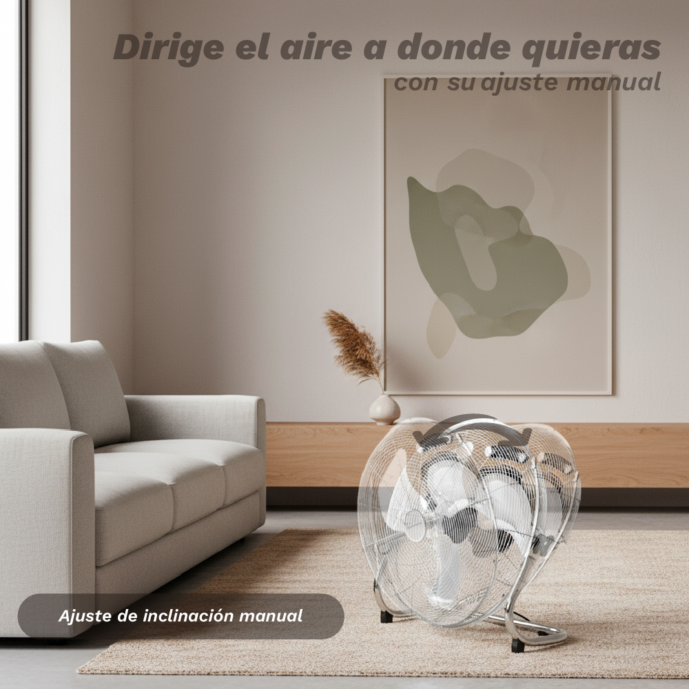 Un ventilador plateado sobre alfombra frente a un sofá. Arte en la pared.