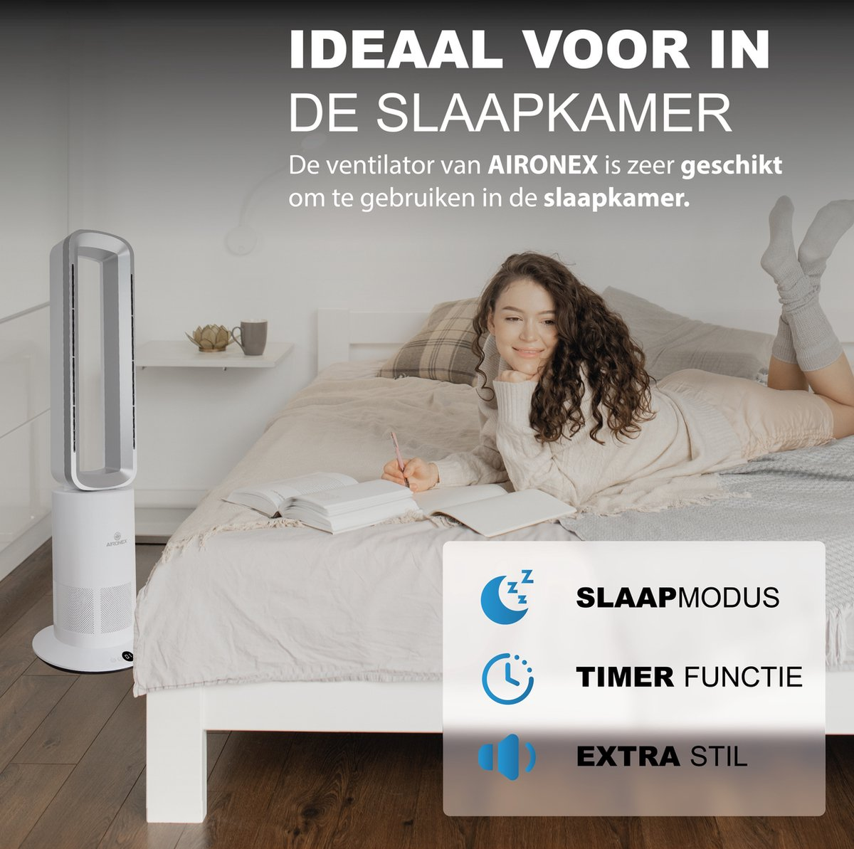 A slim tower fan stands beside a bed with a woman lying on it.