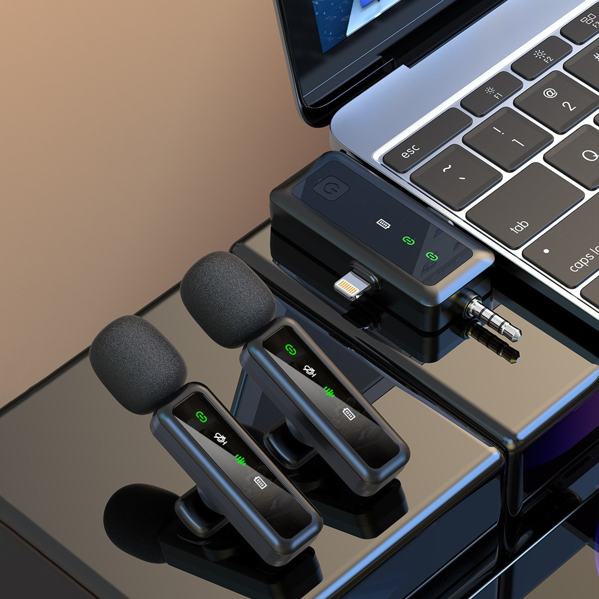 Dwa czarne mikrofony krawatowe z piankowymi osłonami obok laptopa.