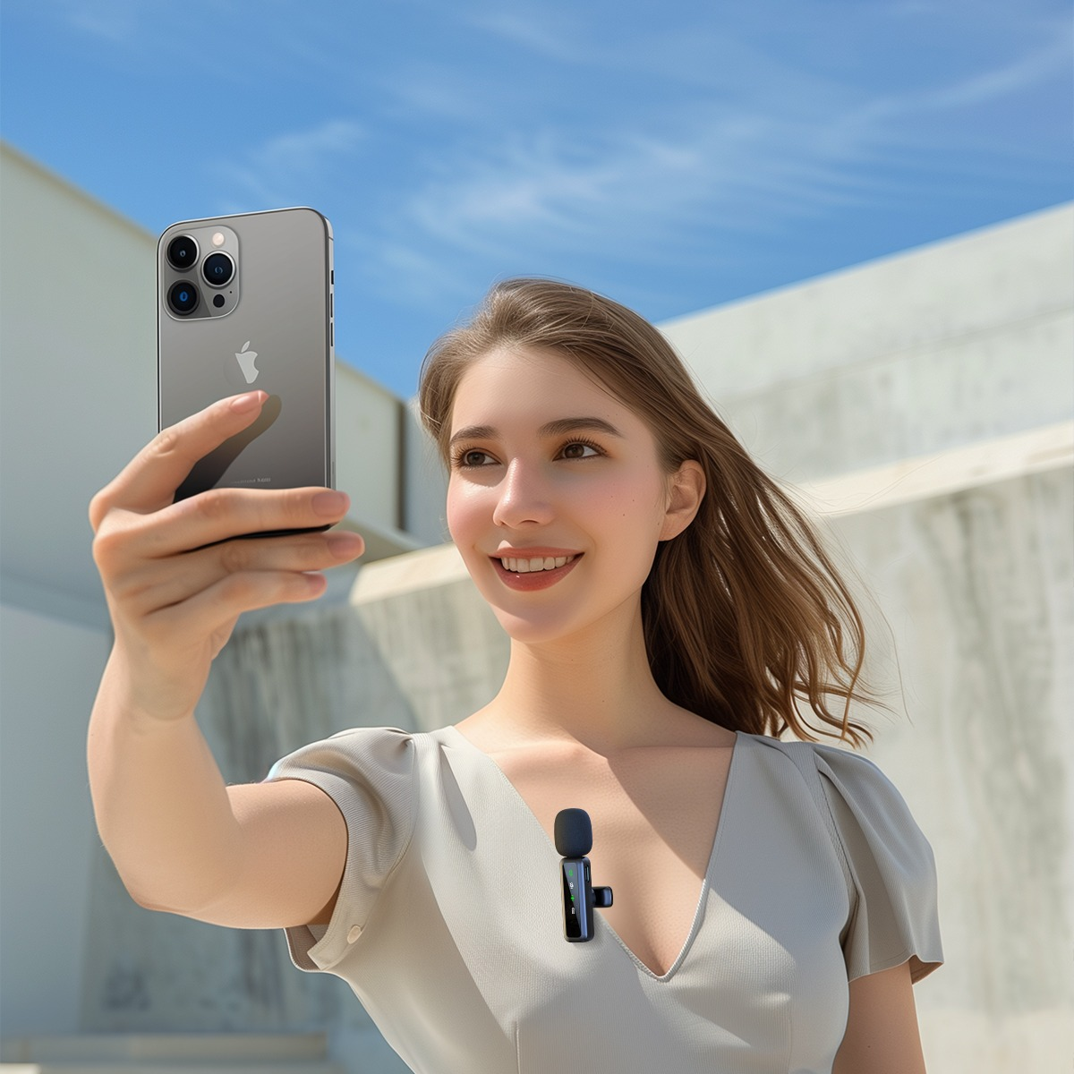 Kobieta robi sobie selfie z iPhone'em, mikrofon przypięty do ubrania.