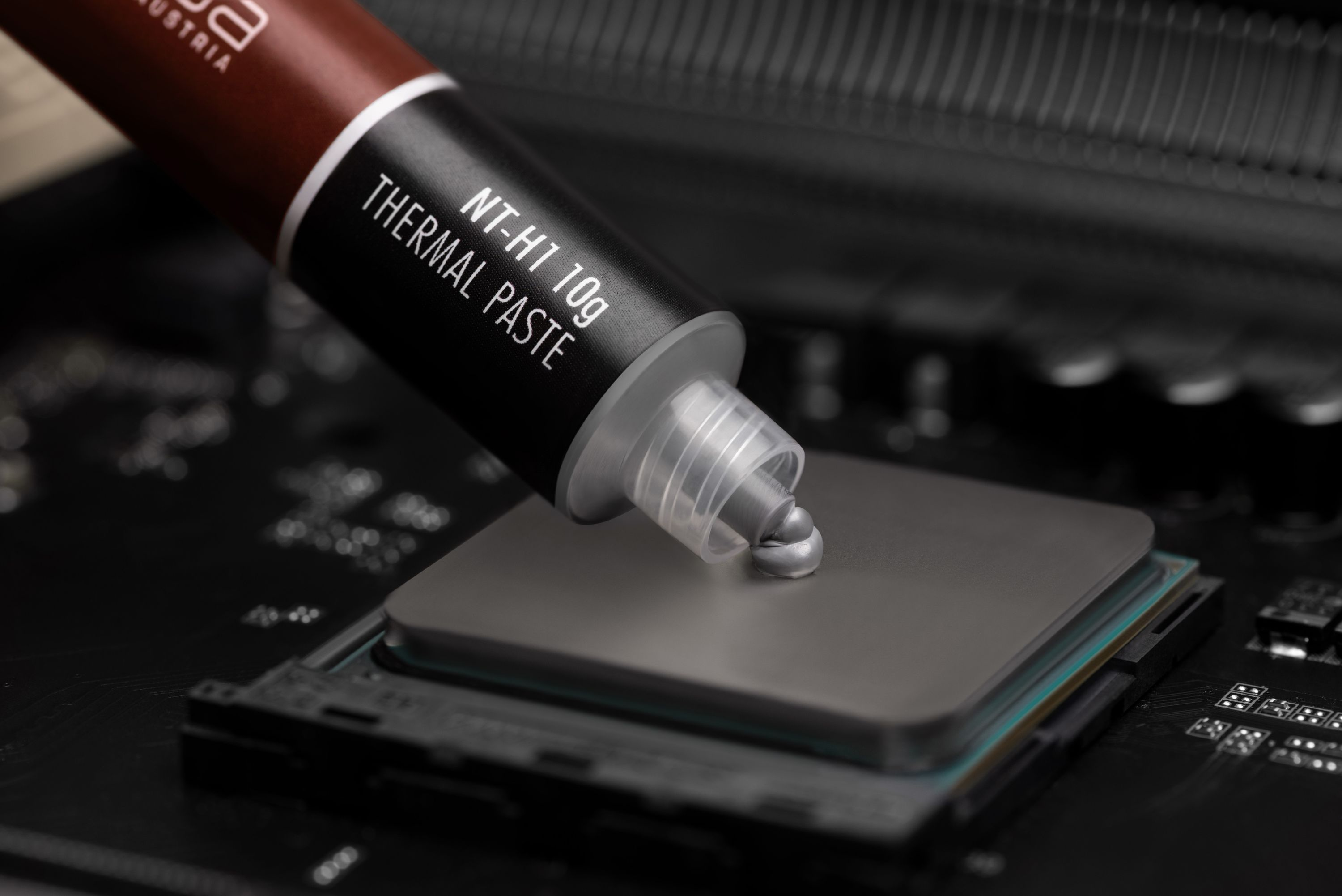 Pasta termoprzewodząca jest nakładana z brązowej tubki na gniazdo procesora na płycie.