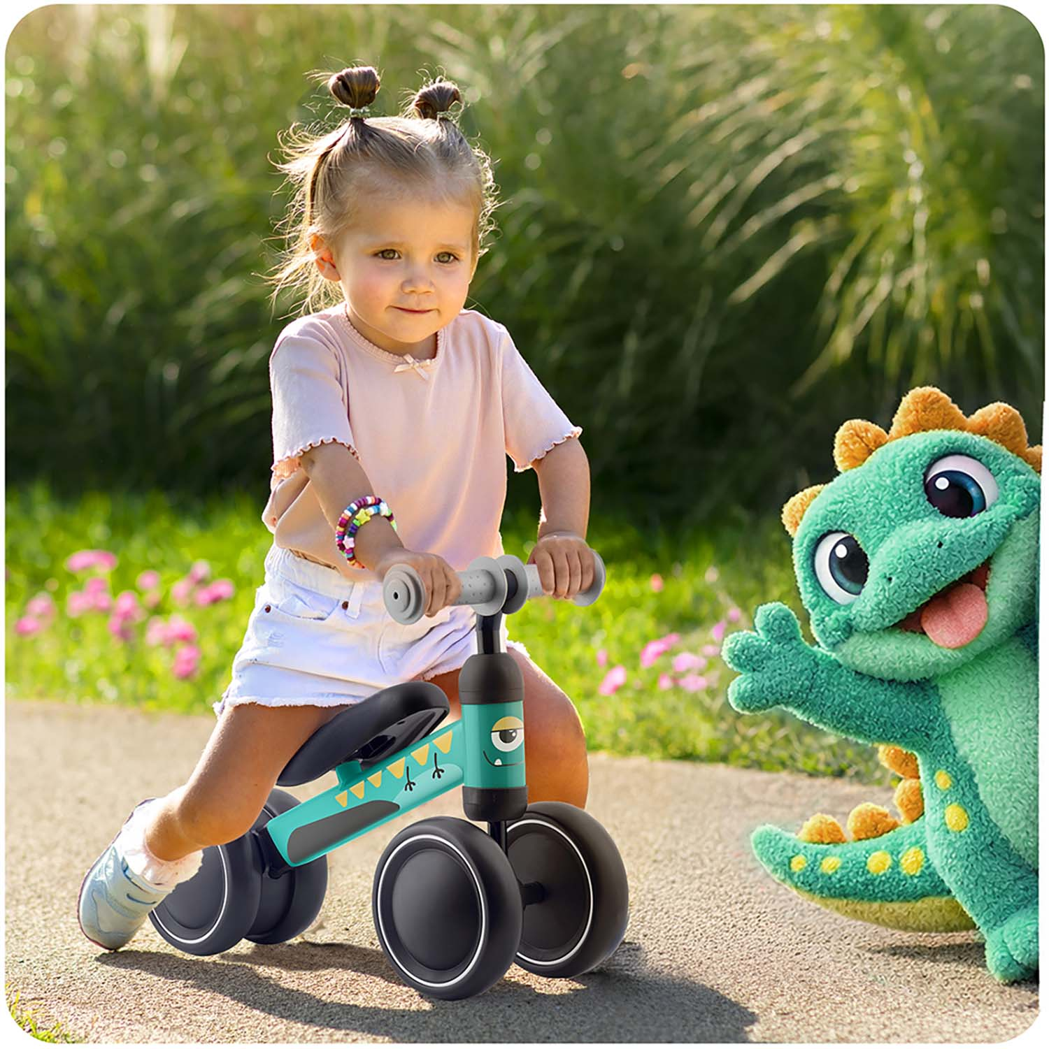 Mała dziewczynka jedzie na rowerku biegowym obok zielonej pluszowej zabawki dinozaura.
