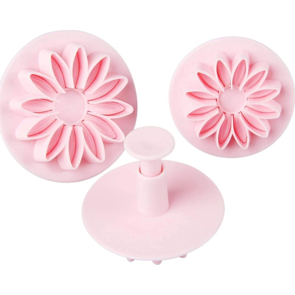 Trois emporte-pièces fleurs roses de différentes tailles. Un a une poignée.